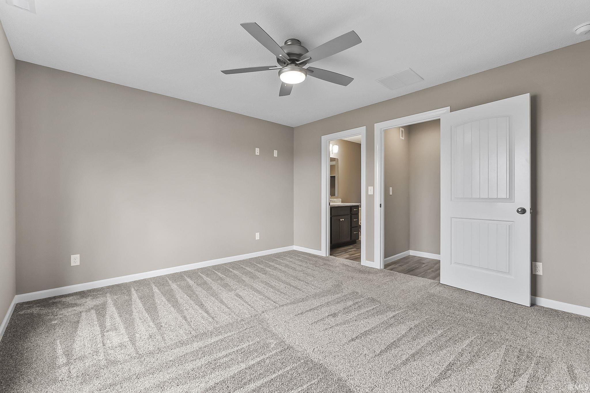 Unfurnished bedroom with light carpet, ensuite bath, and ceiling fan