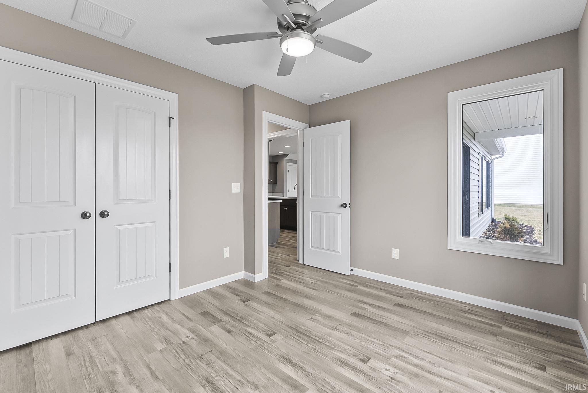 Unfurnished bedroom featuring light wood-style flooring, a closet, and a ceiling fan