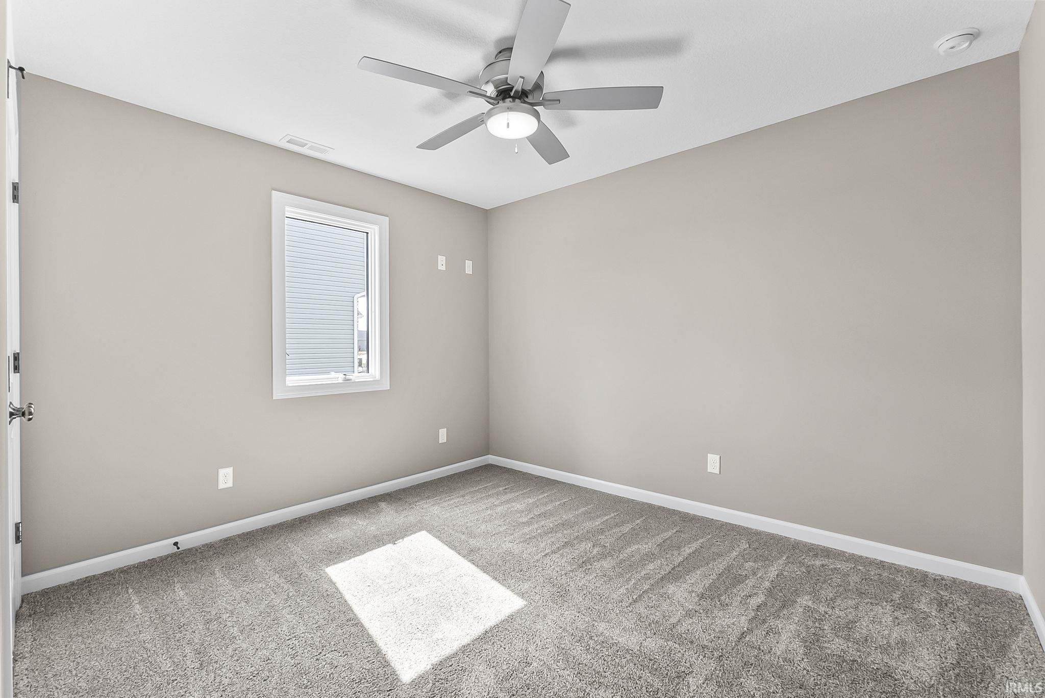 Empty room with a ceiling fan and light carpet