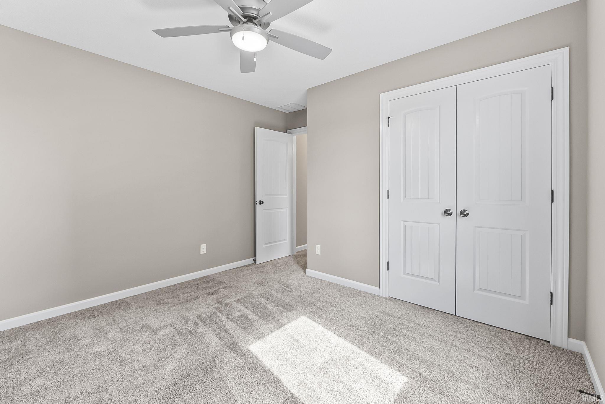 Unfurnished bedroom featuring light carpet, a closet, and a ceiling fan