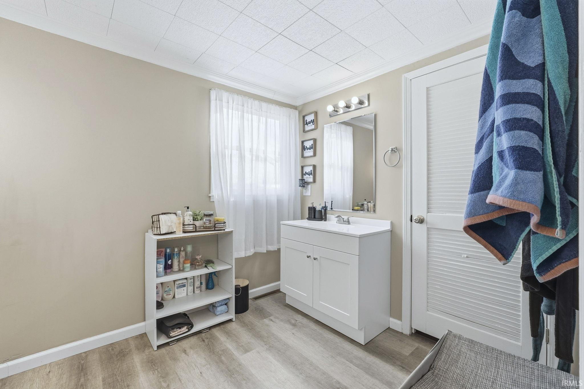 Bathroom with vanity, light wood-style flooring, and ornamental molding