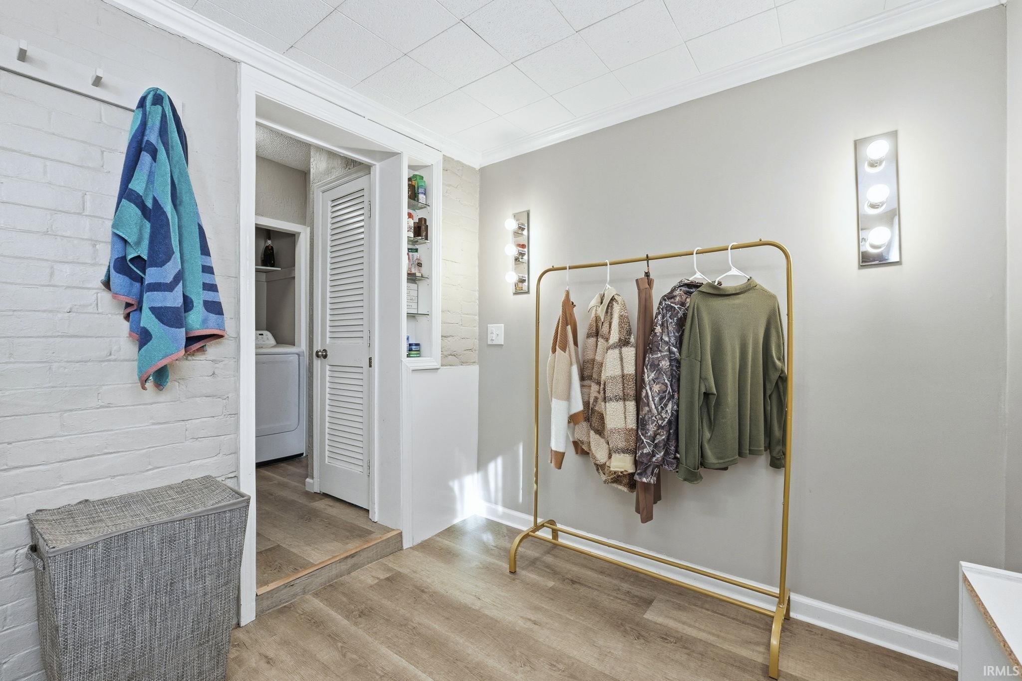 Bathroom featuring wood finished floors, washer / dryer, and crown molding