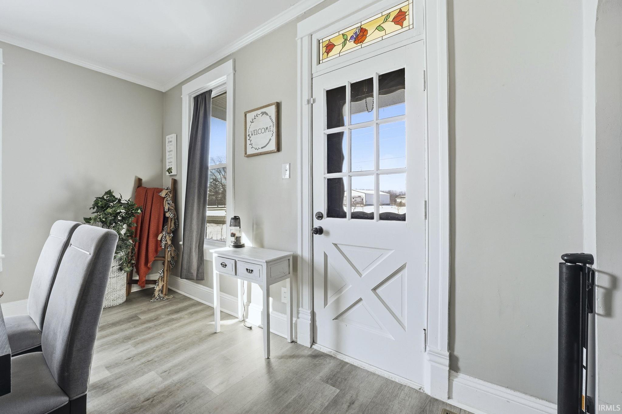 Doorway to outside with wood finished floors and crown molding