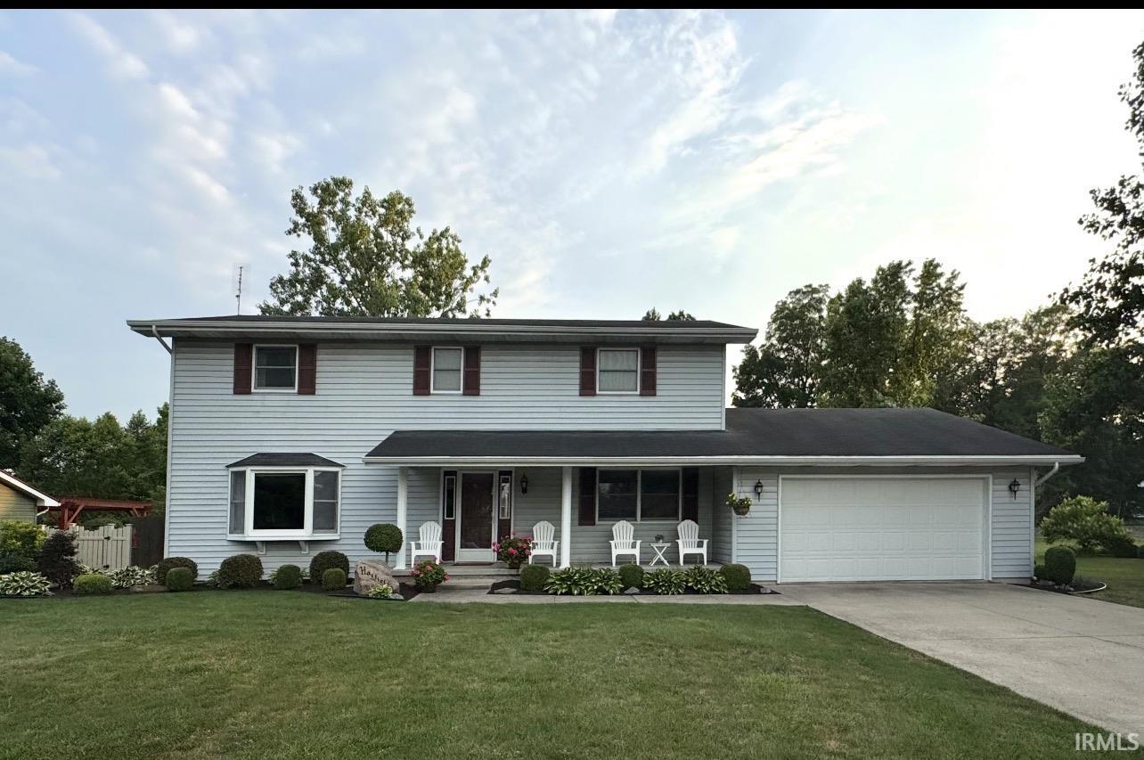Traditional home featuring a porch, a front lawn, concrete driveway, and an attached garage