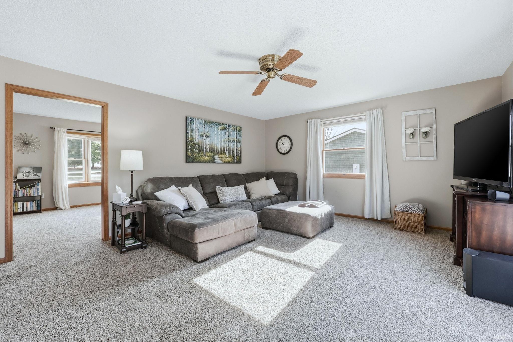 Living area featuring carpet flooring and ceiling fan