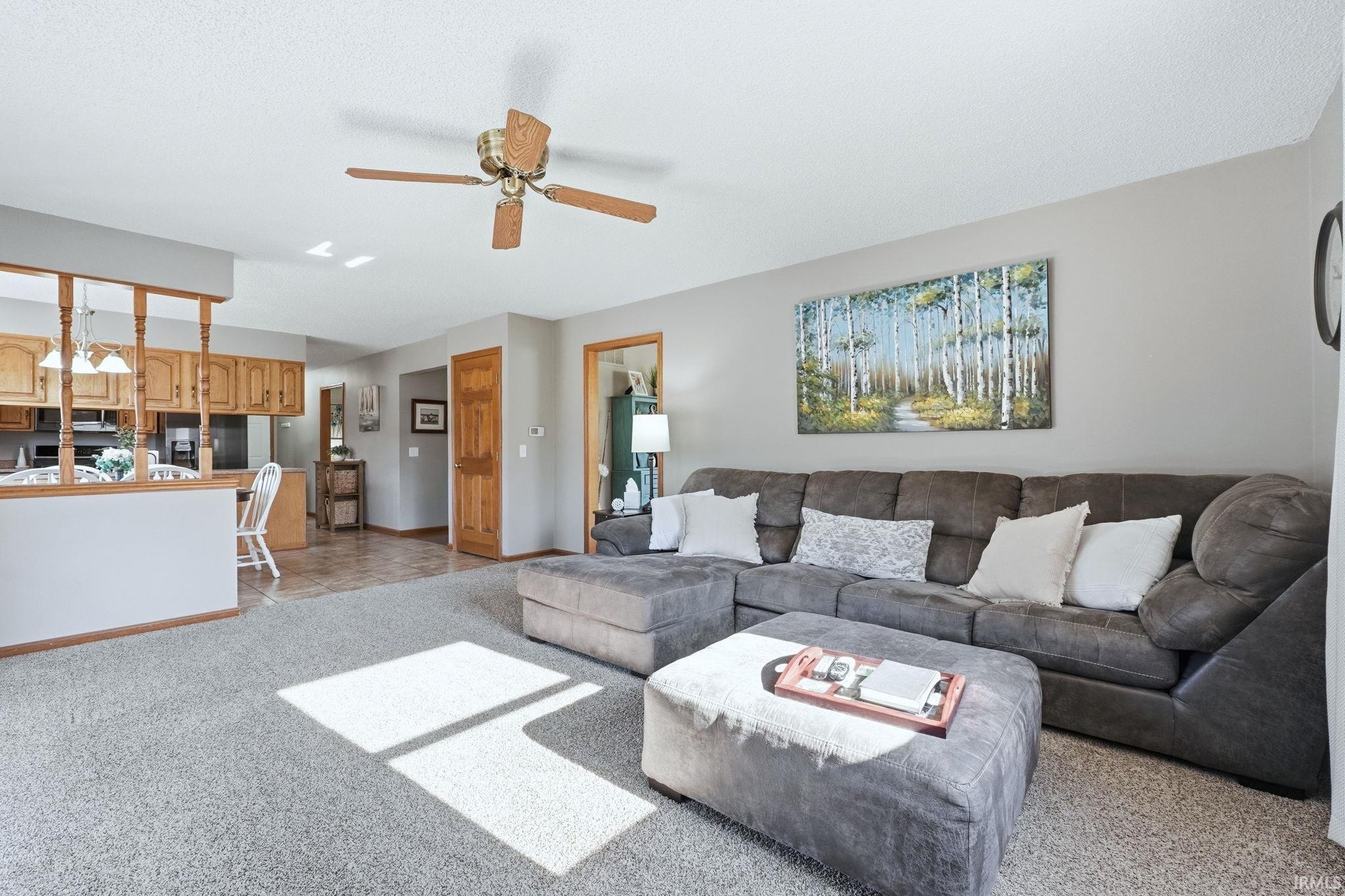 Living area with ceiling fan and light carpet
