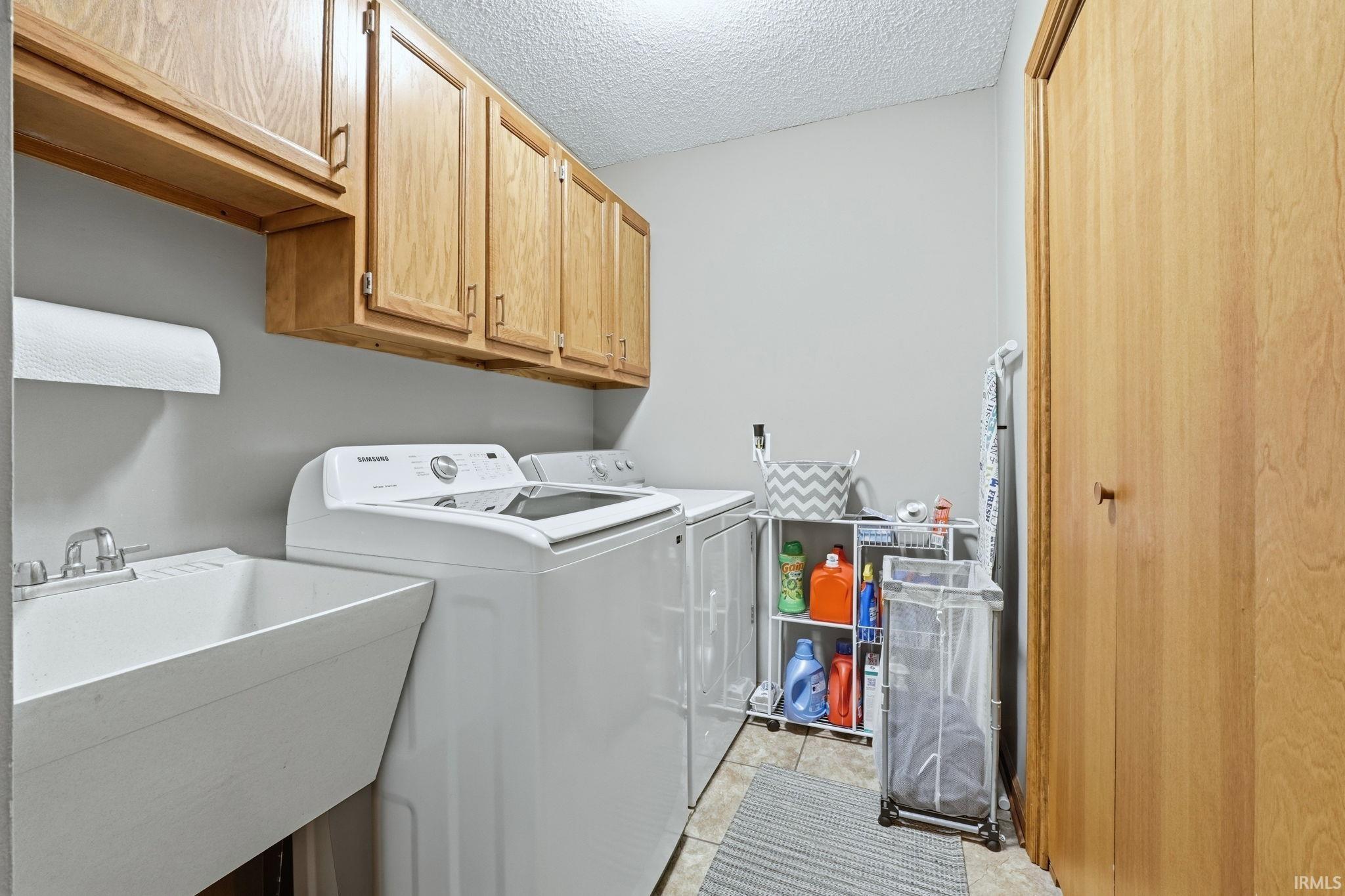 Laundry room with a textured ceiling, cabinet space, and washer and dryer