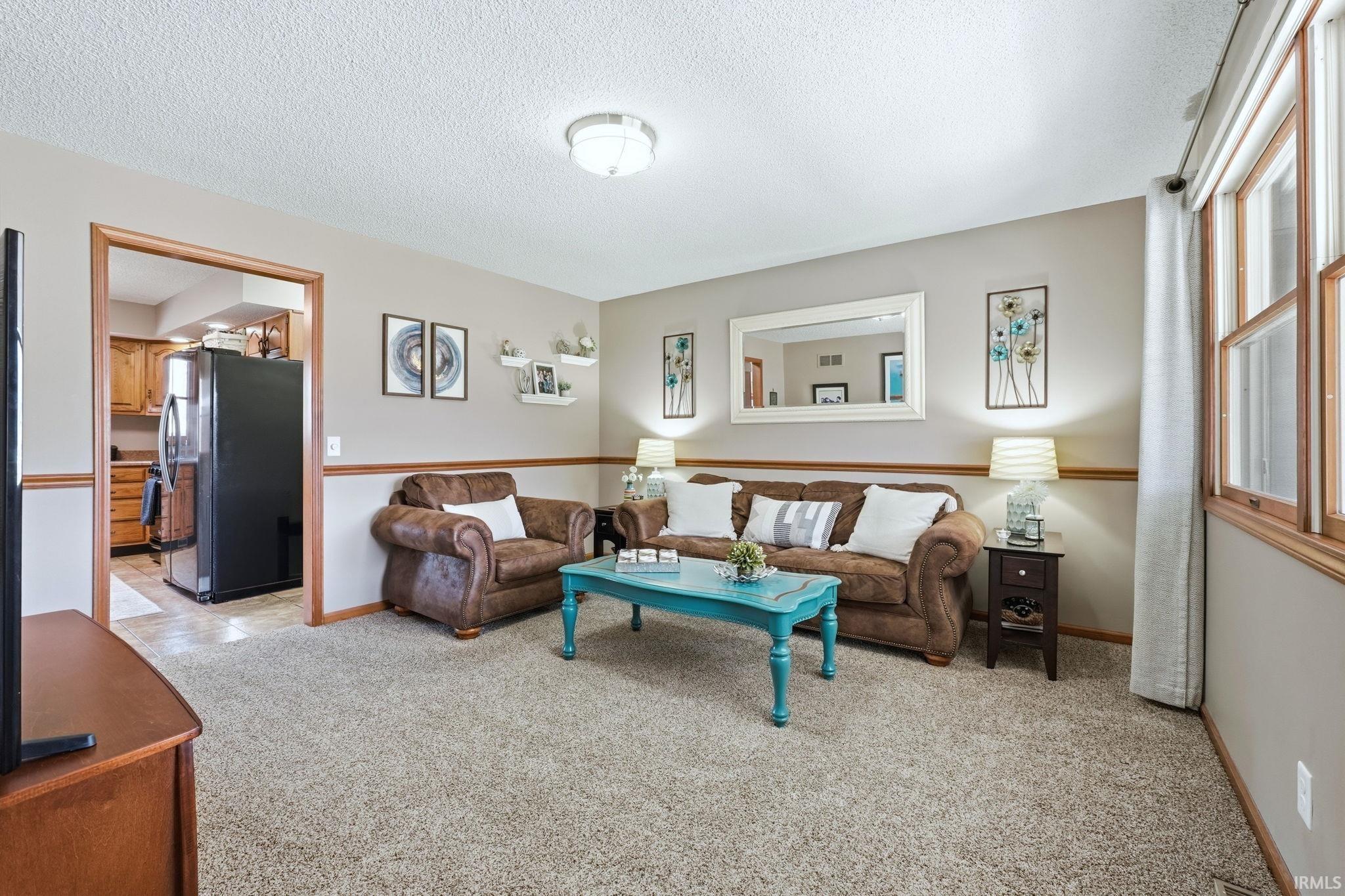 Living area with light colored carpet and a textured ceiling