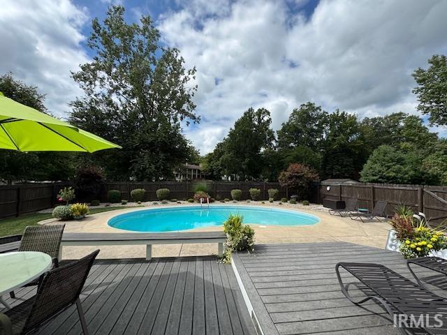 View of swimming pool featuring a deck, a fenced backyard, patio surround, and outdoor dining area