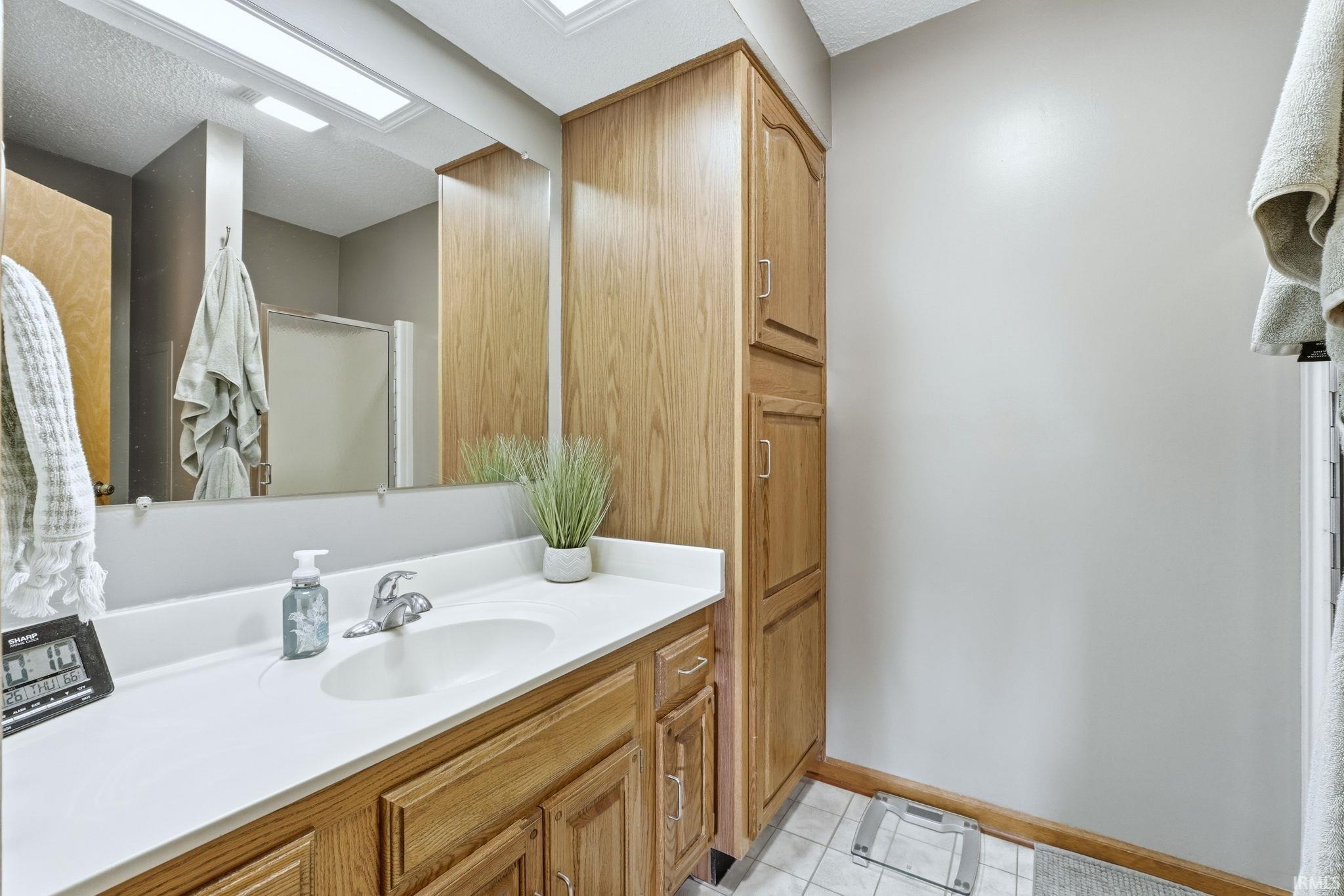 Bathroom with vanity, a stall shower, light tile patterned flooring, and a textured ceiling