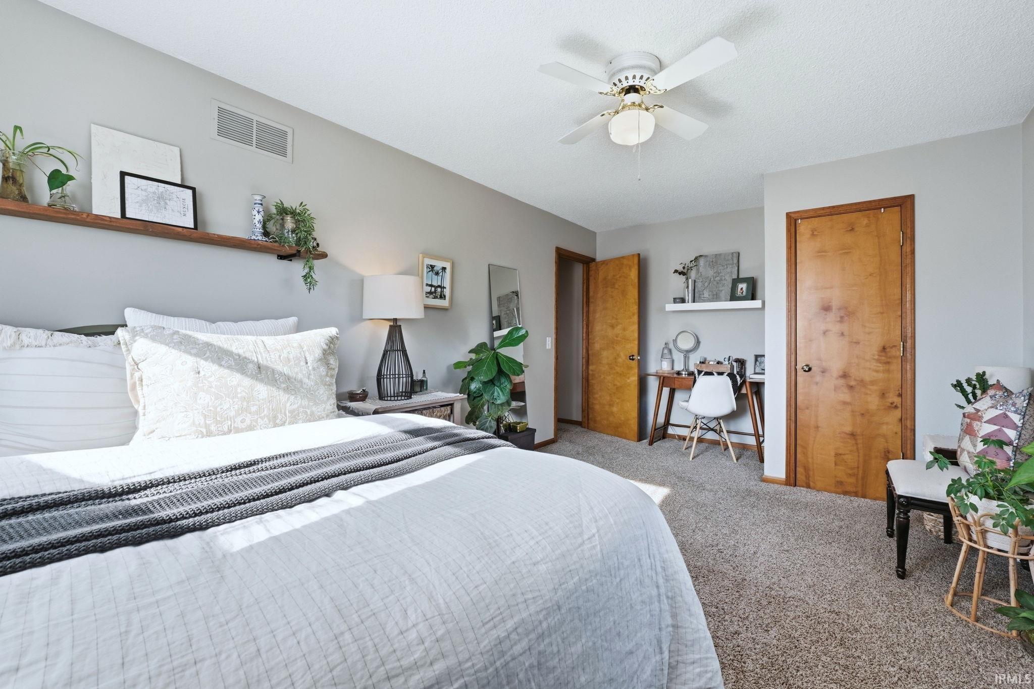Carpeted bedroom with a desk, ceiling fan, and baseboard heating