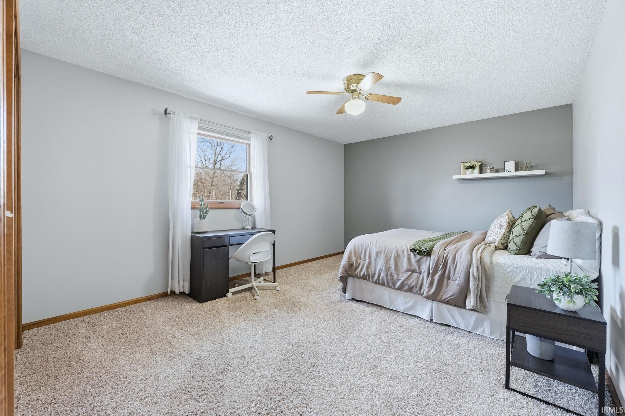 Bedroom with light colored carpet, a textured ceiling, and a ceiling fan