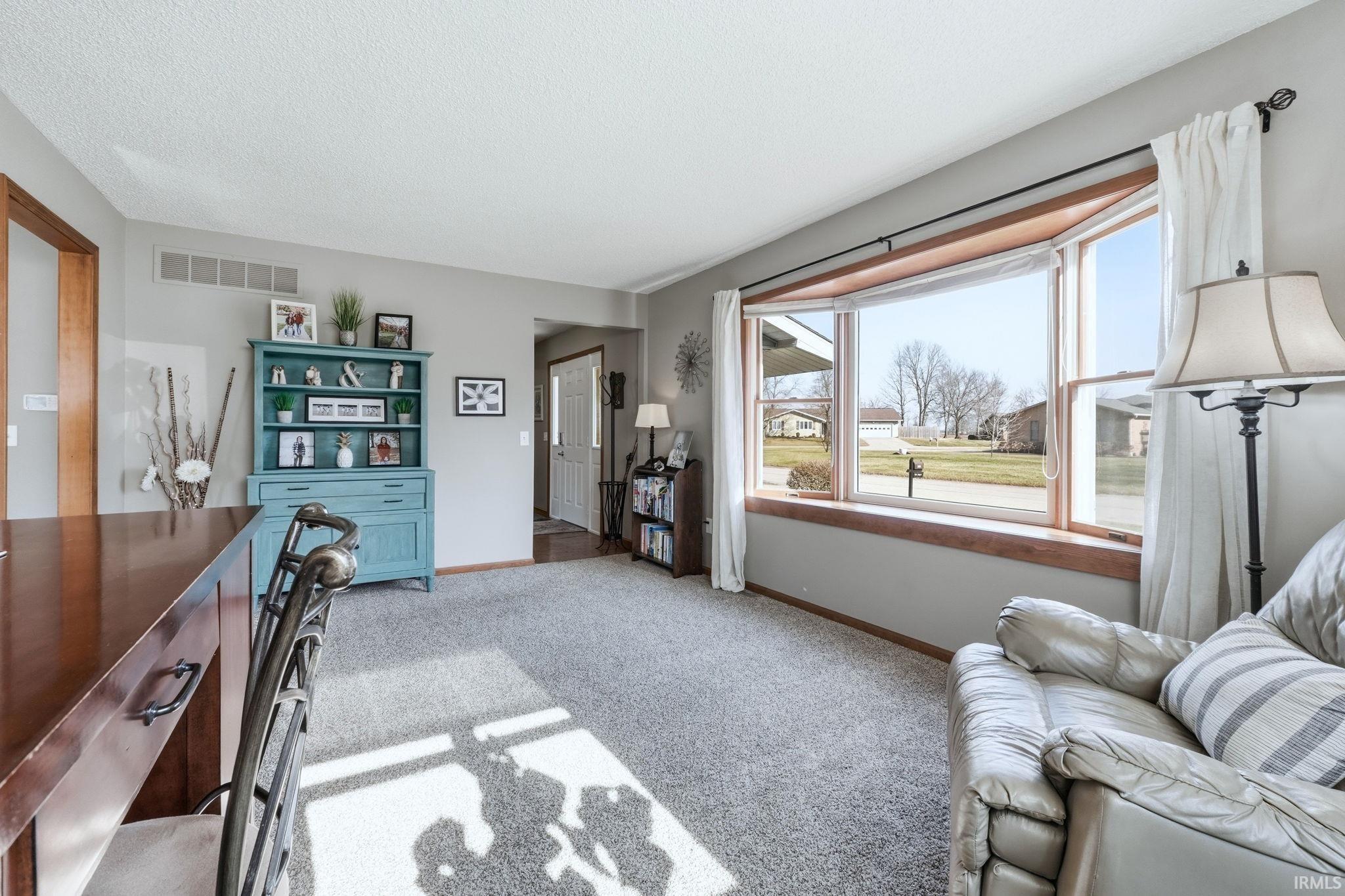 Living room with light colored carpet and a textured ceiling