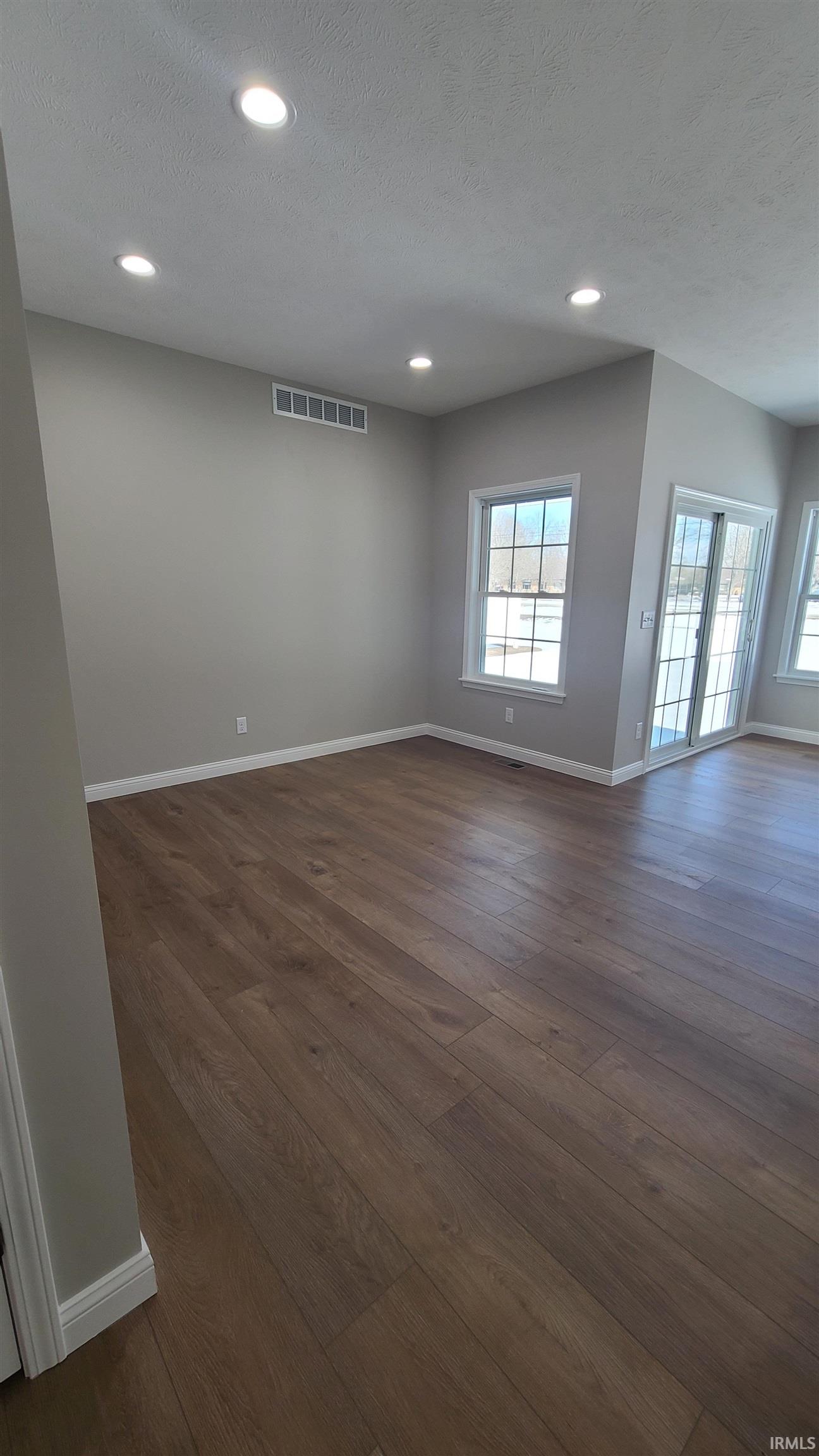 Spare room featuring dark wood-style floors, recessed lighting, and a textured ceiling