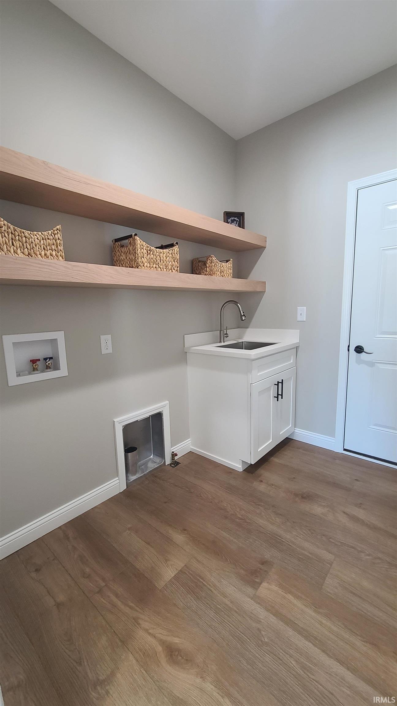 Laundry area with light wood-style floors, washer hookup, and cabinet space