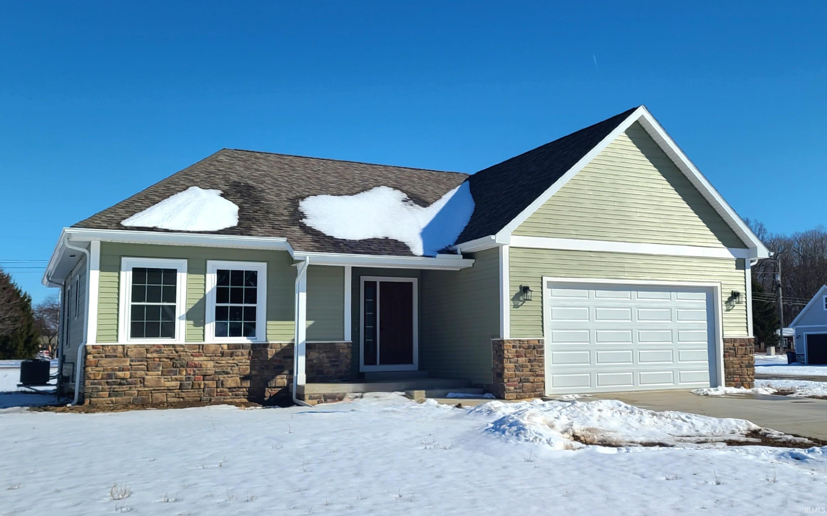 View of front of property featuring stone siding, a garage, and a porch