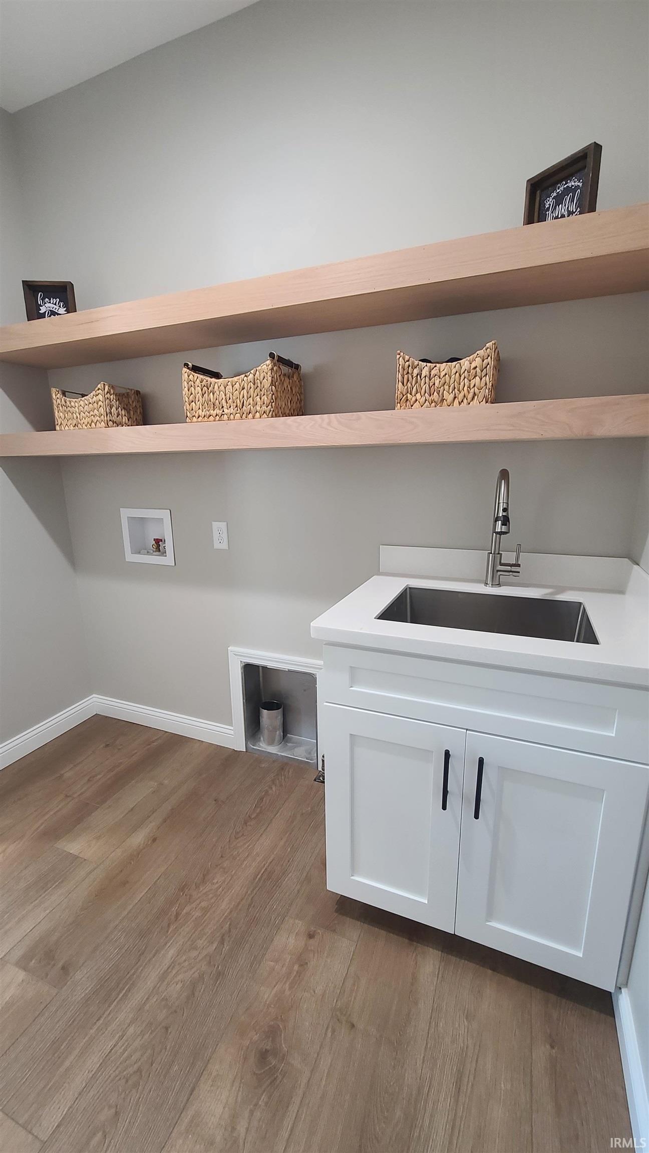 Laundry area featuring light wood-style flooring, washer hookup, and cabinet space
