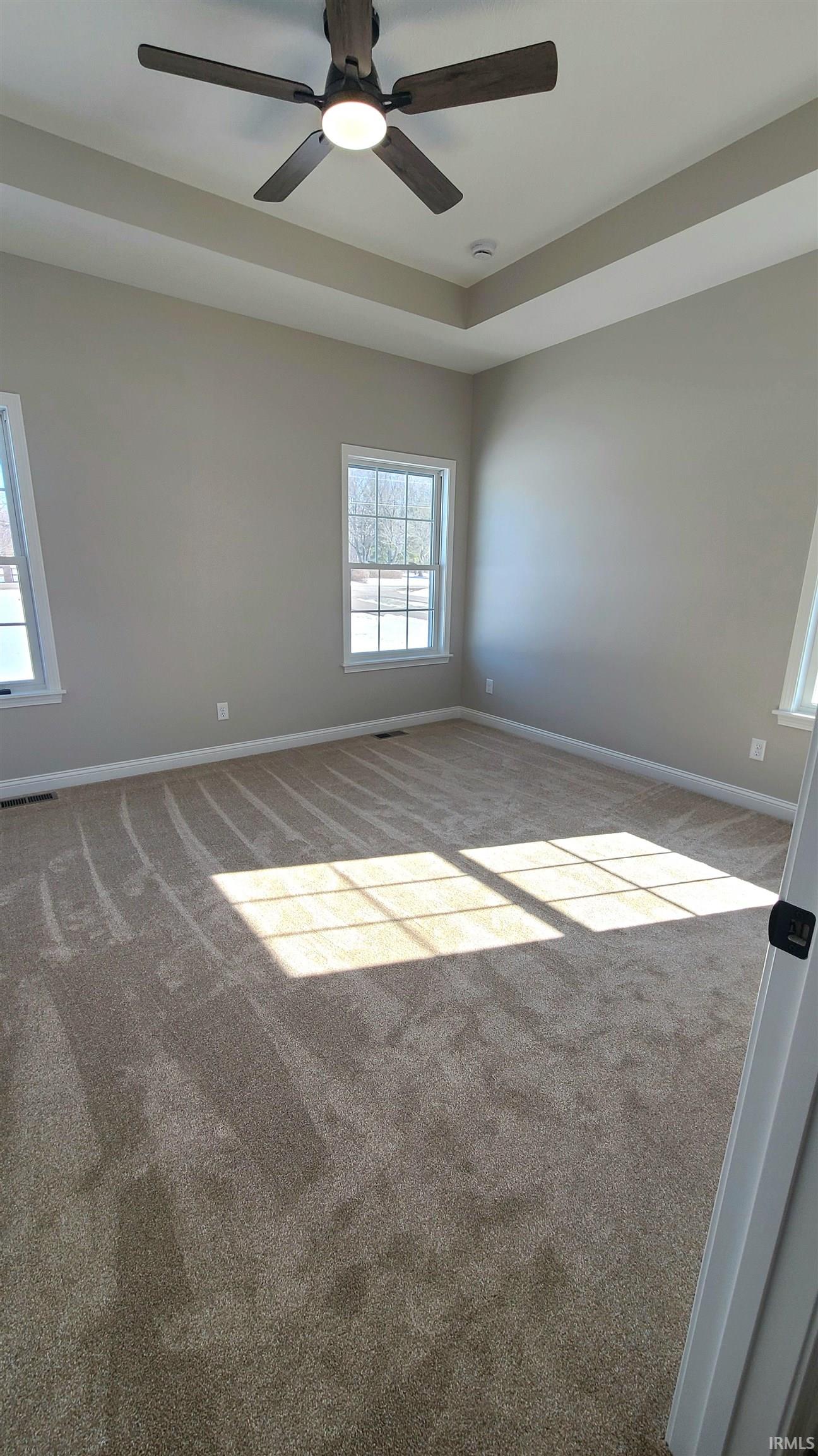 Unfurnished room with ceiling fan, carpet, and a raised ceiling