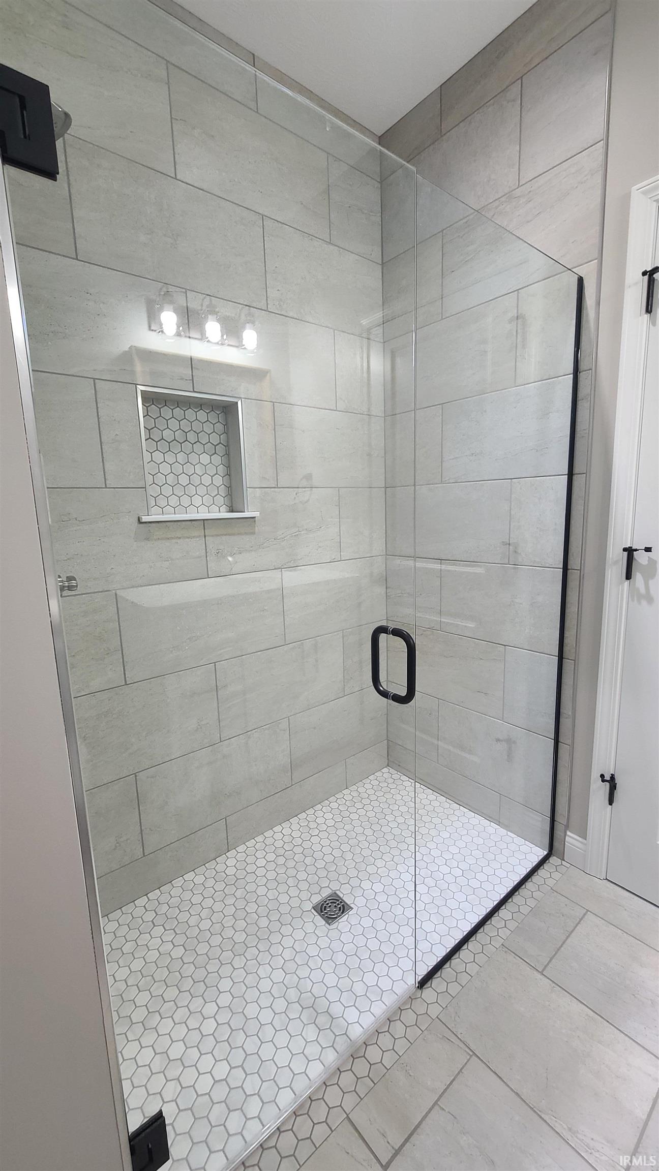 Full bath with a shower stall and tile patterned flooring