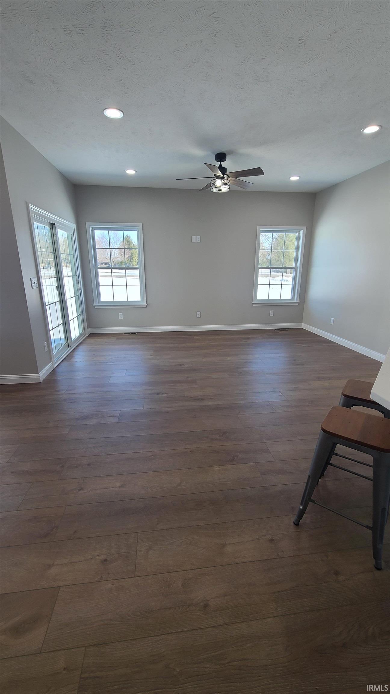 Unfurnished living room with dark wood finished floors, recessed lighting, a textured ceiling, and a ceiling fan