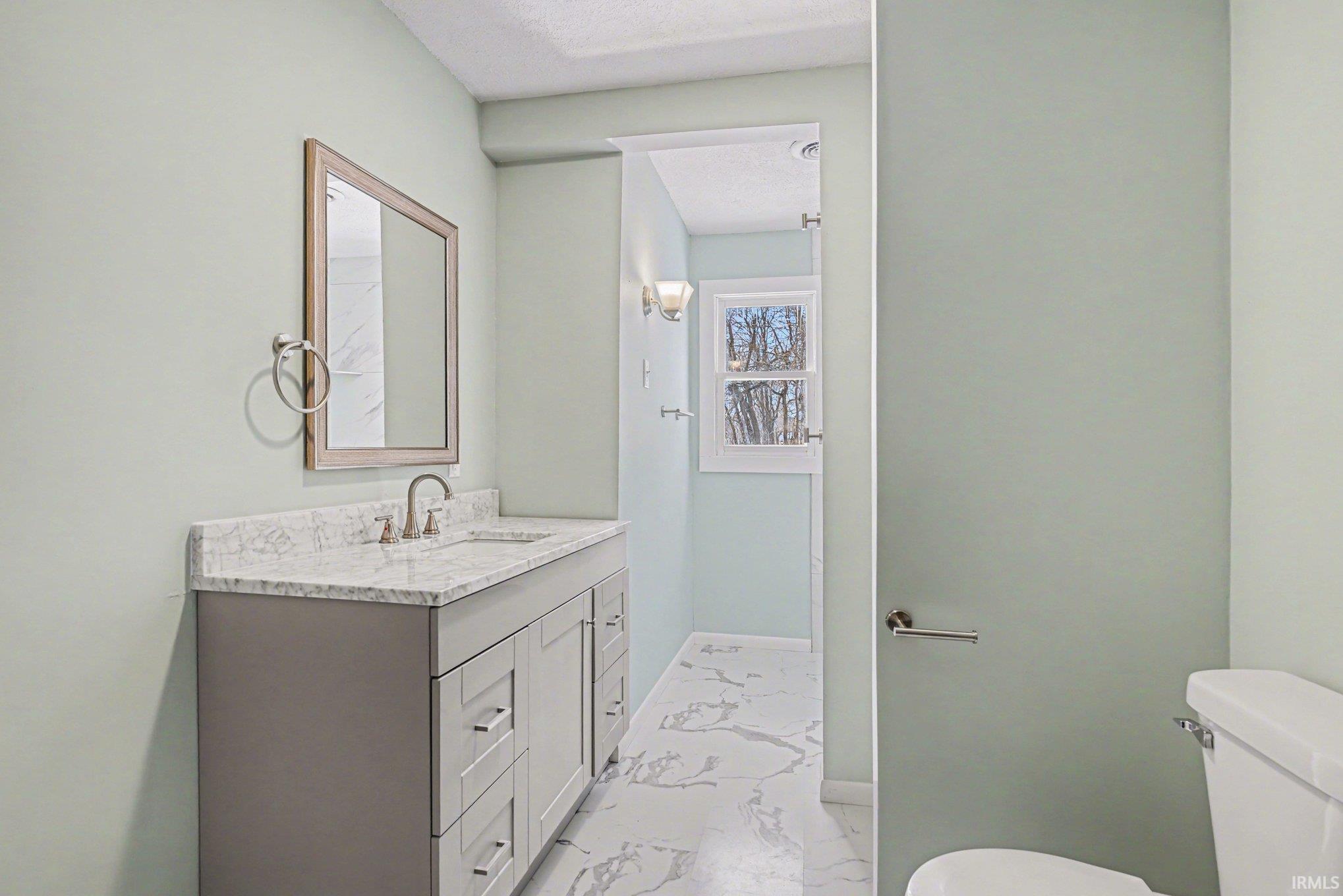 Half bath featuring vanity and light marble finish flooring