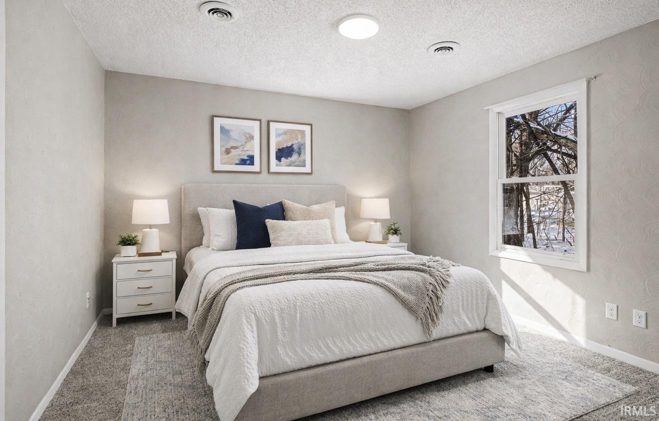 Bedroom featuring carpet flooring, a textured wall, and a textured ceiling