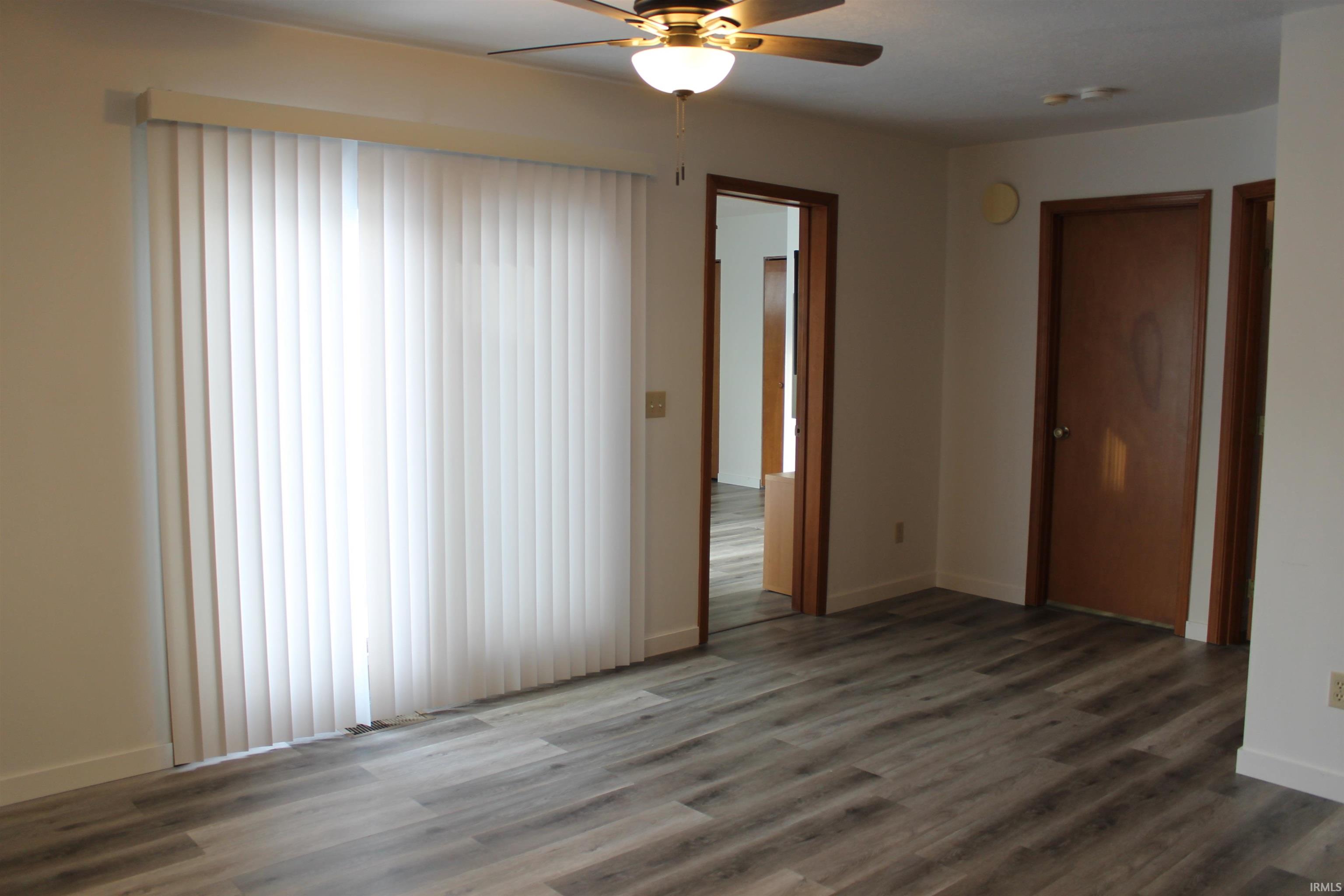 Unfurnished room featuring dark wood-type flooring and a ceiling fan
