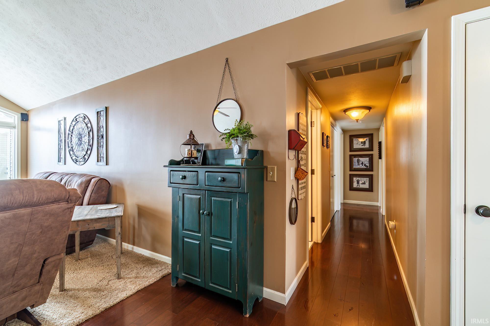 Hall featuring dark wood-style floors leading to bedrooms laundry and bathrooms