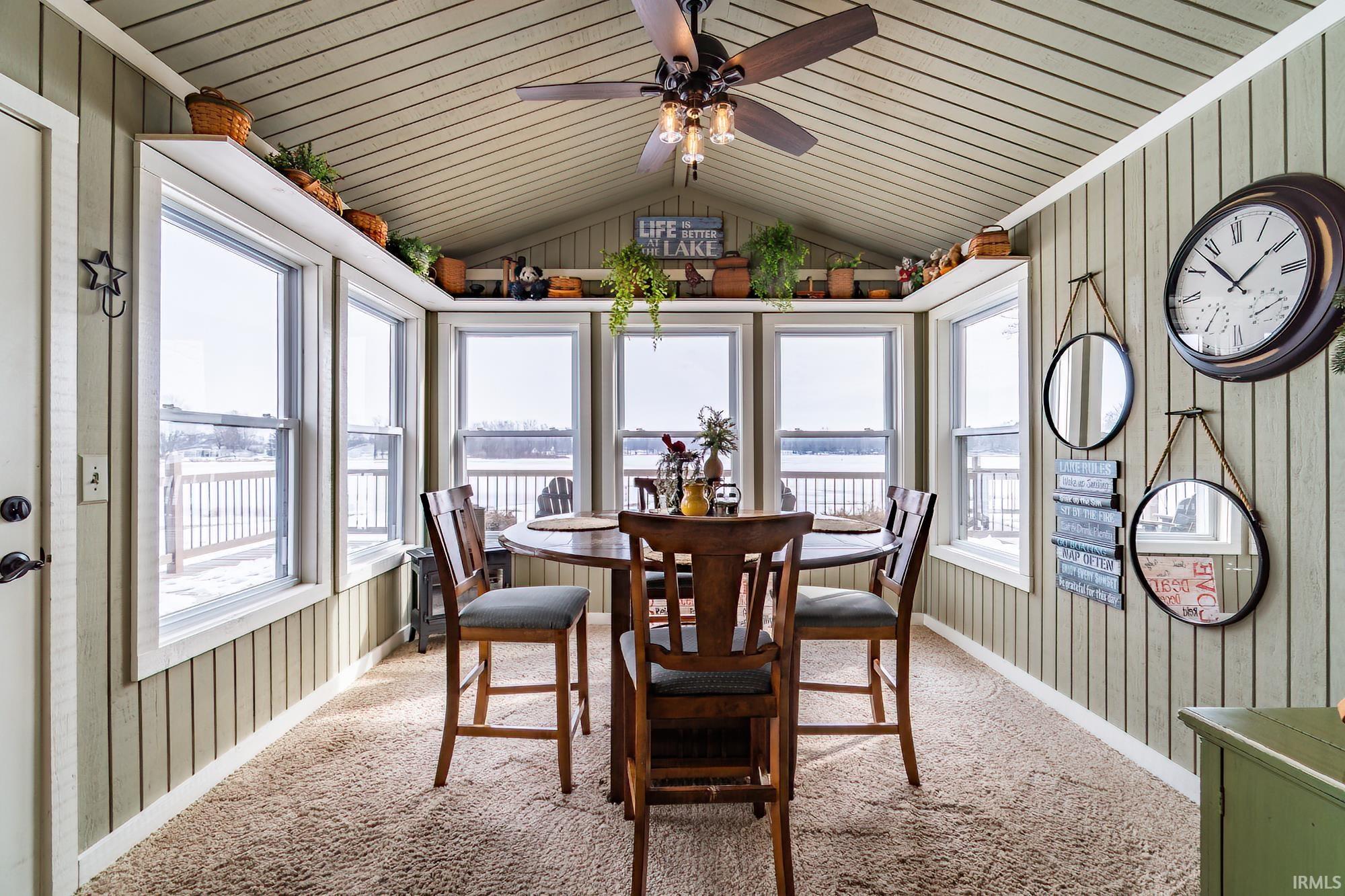 Carpeted dining space with wood walls and a ceiling fan