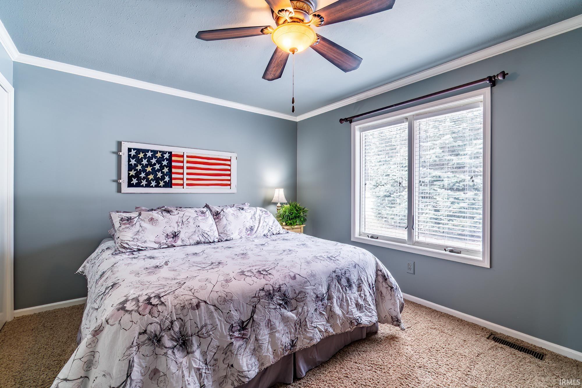 Bedroom featuring ornamental molding, carpet flooring, and a ceiling fan