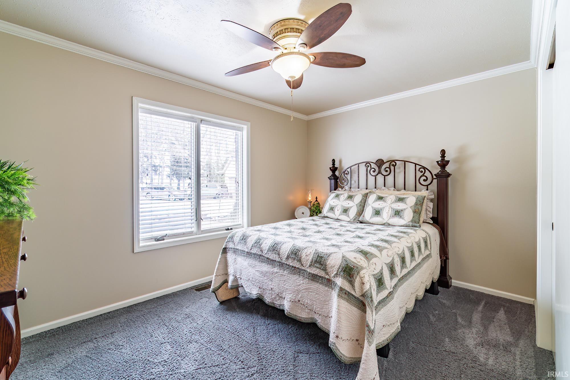 Carpeted bedroom with crown molding and ceiling fan