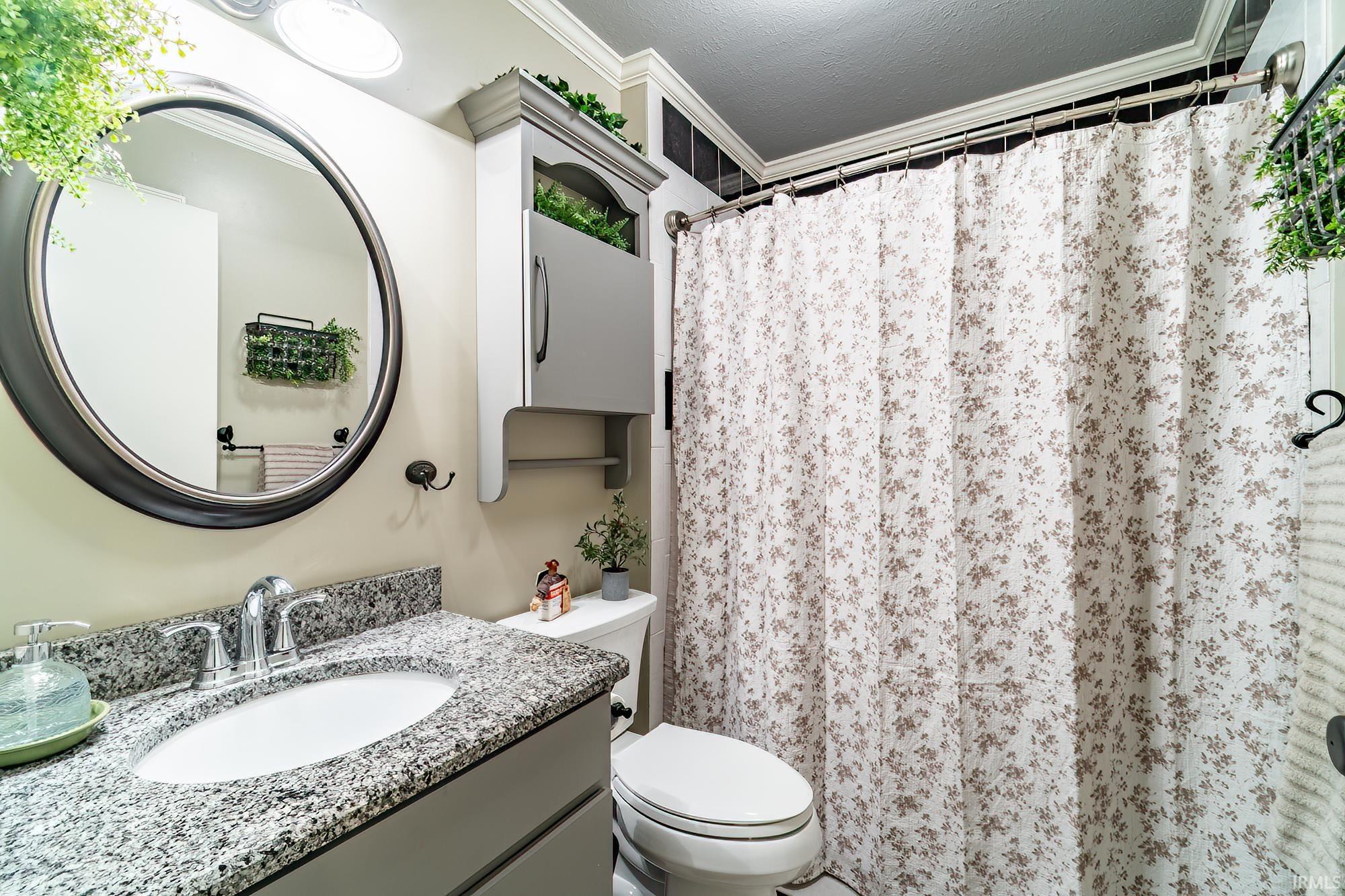 Bathroom featuring vanity, a shower with curtain, ornamental molding, and a textured ceiling