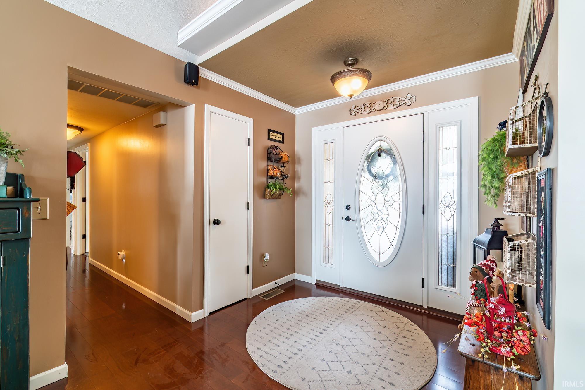 Foyer entrance featuring dark wood-type flooring and ornamental molding and a closet