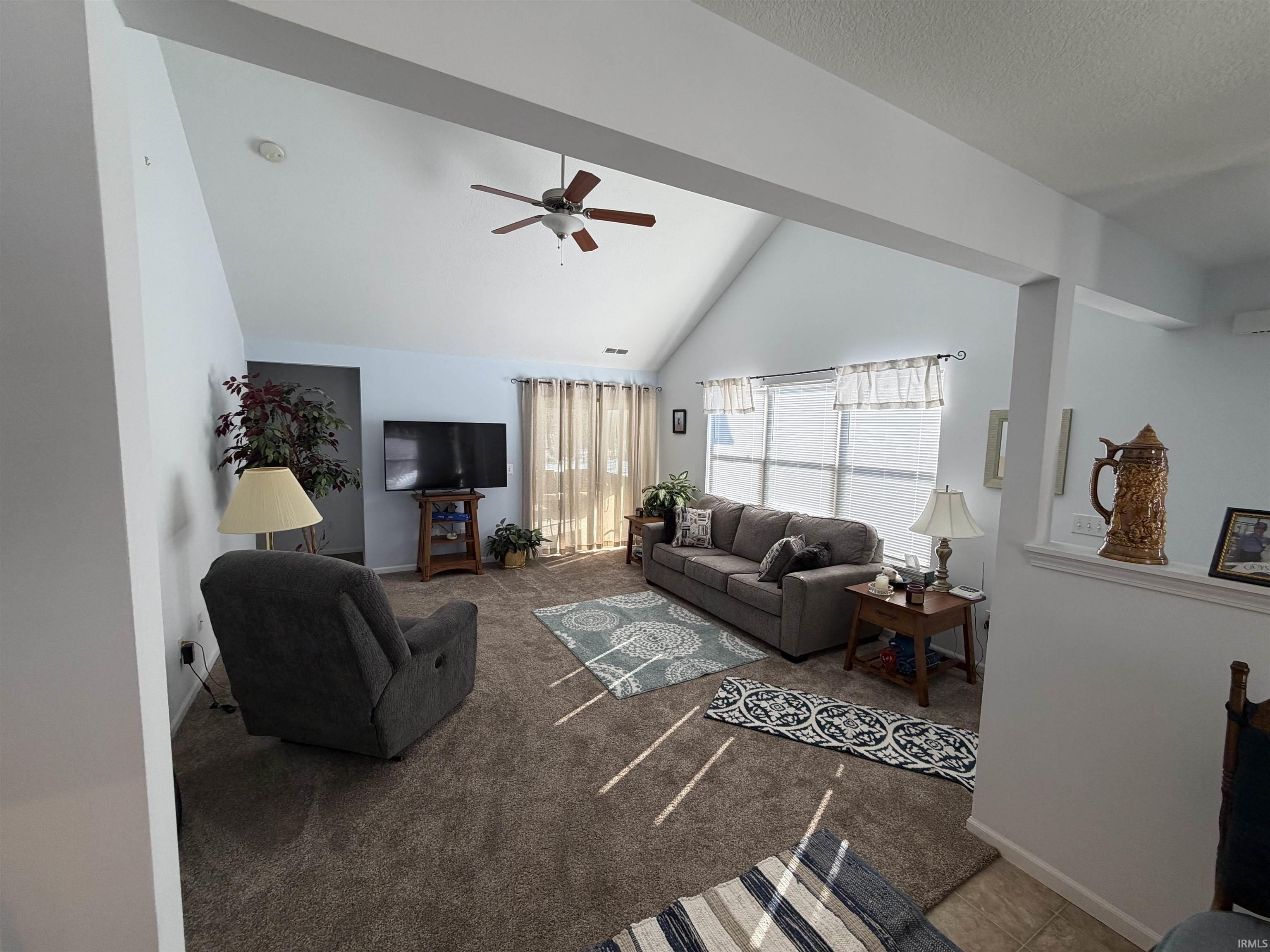 Living area featuring carpet flooring, lofted ceiling, and a ceiling fan