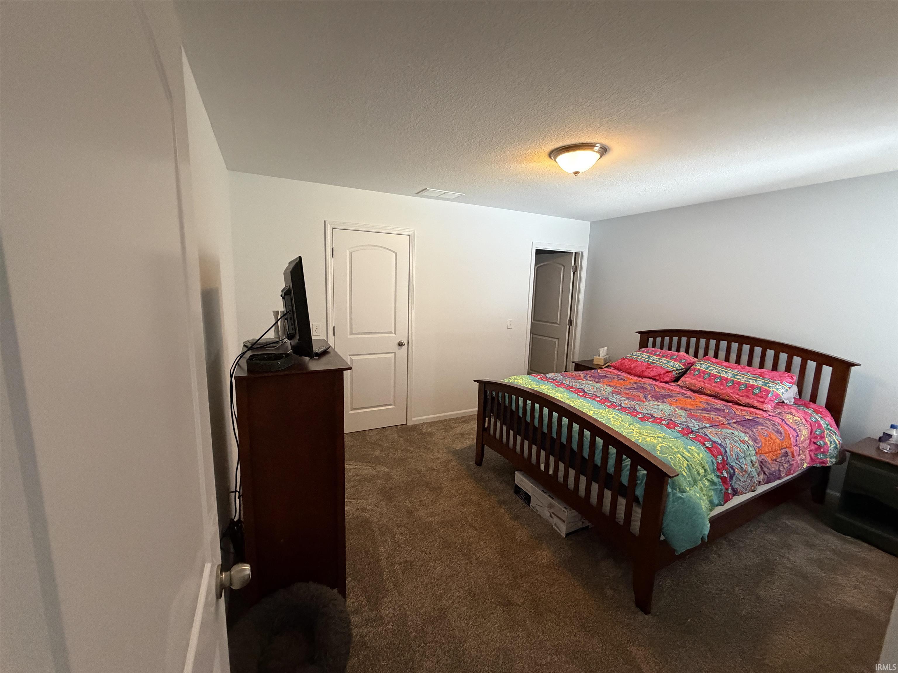Bedroom with dark colored carpet and a textured ceiling