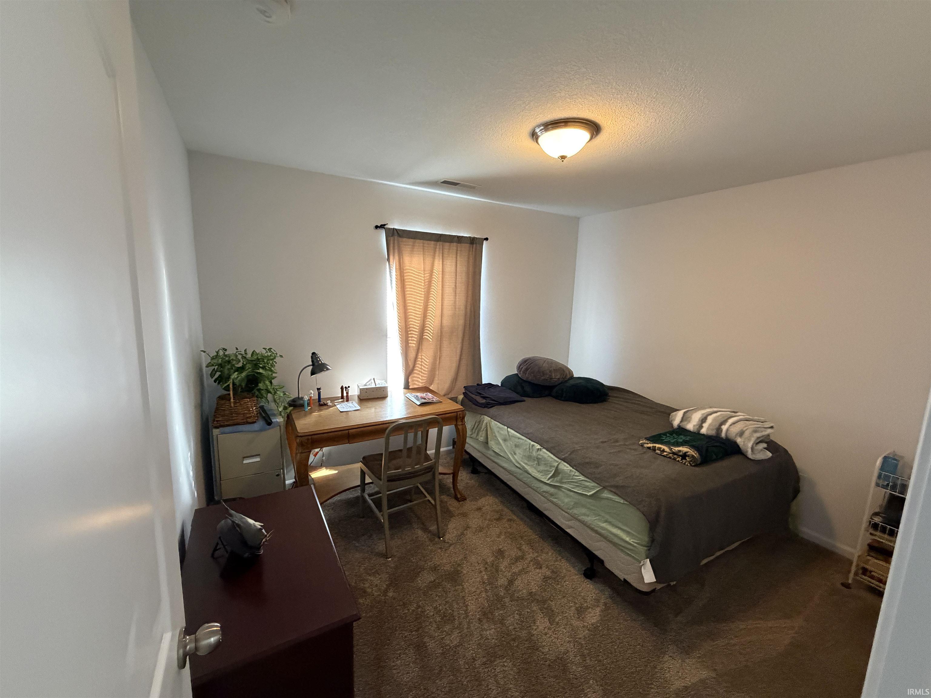 Bedroom with an office area and dark colored carpet