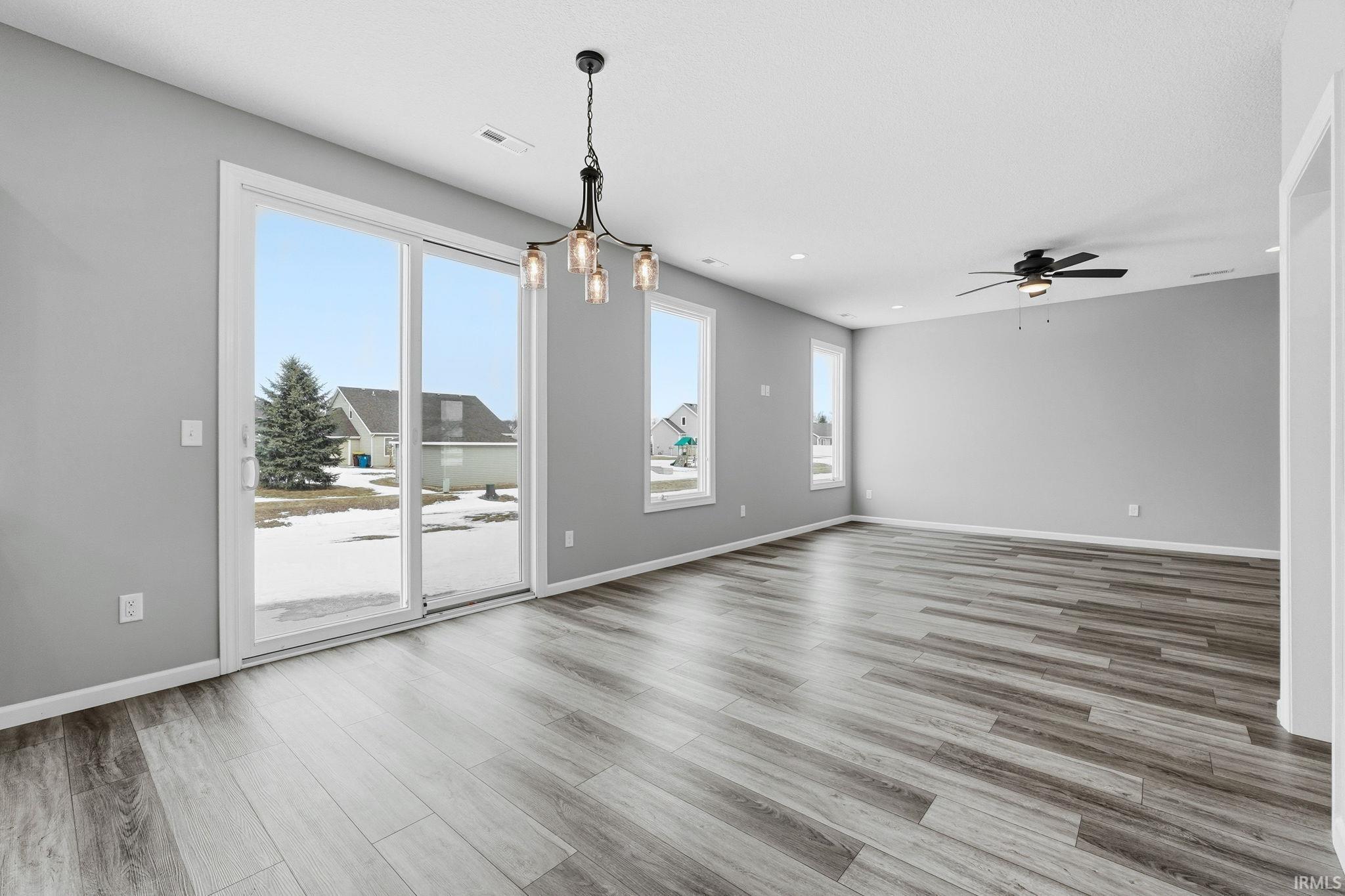 Spare room with hanging lights, light wood-type flooring, and ceiling fan