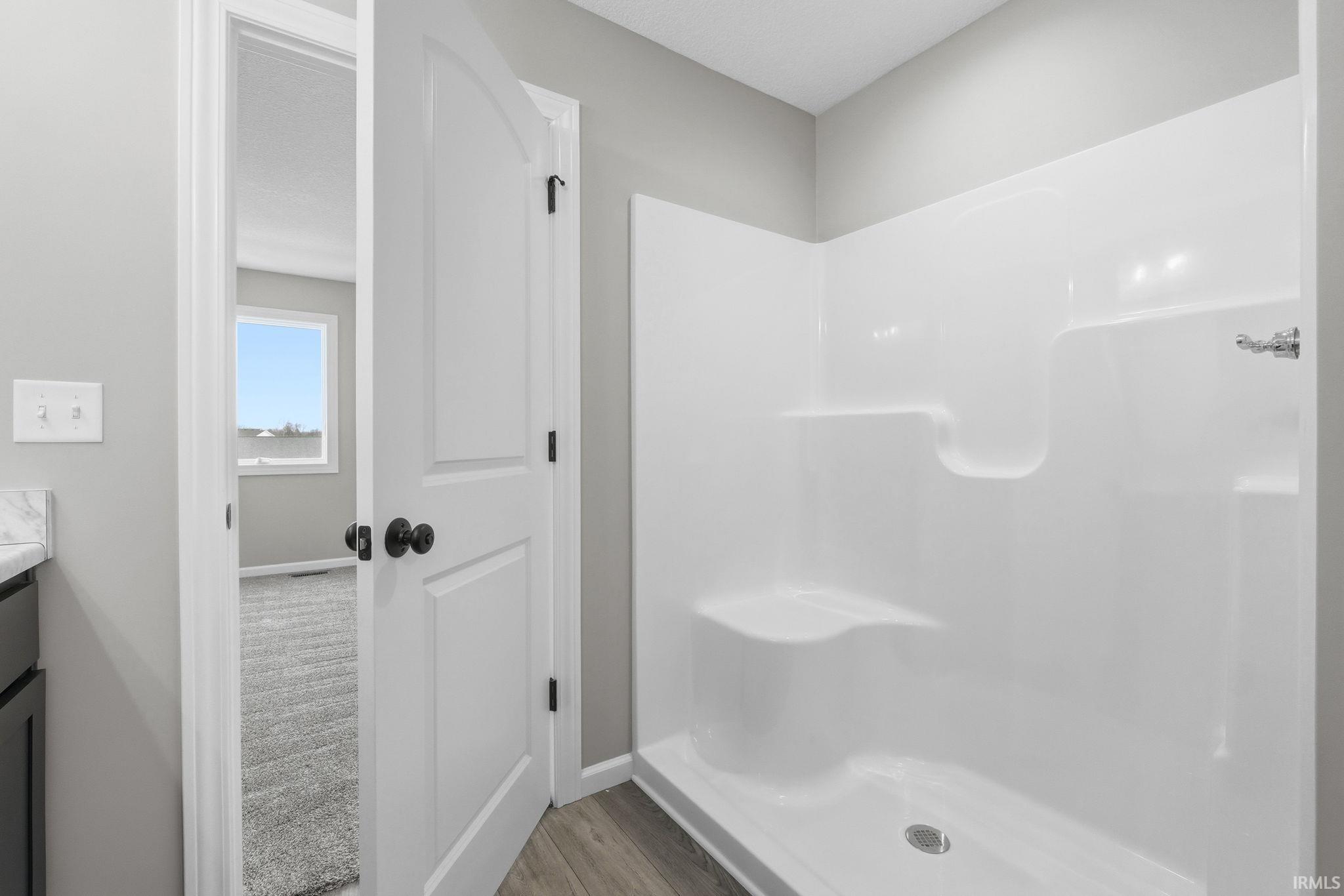 Full bathroom with a shower stall, vanity, and light wood-type flooring