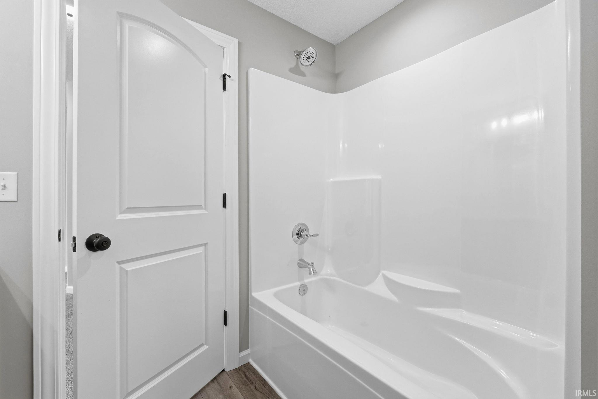 Bathroom with bathing tub / shower combination and wood finished floors