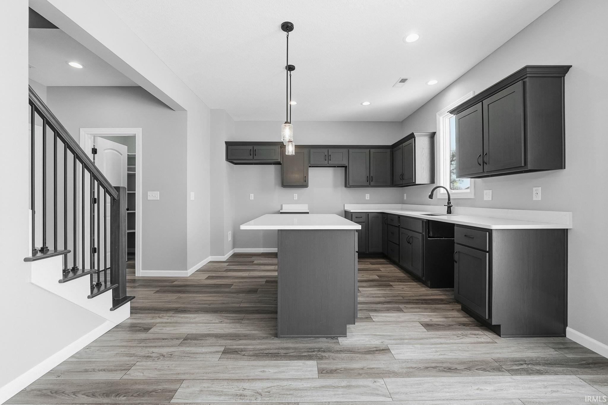 Kitchen featuring light wood-style floors, hanging light fixtures, a kitchen island, a breakfast bar, and gray cabinets