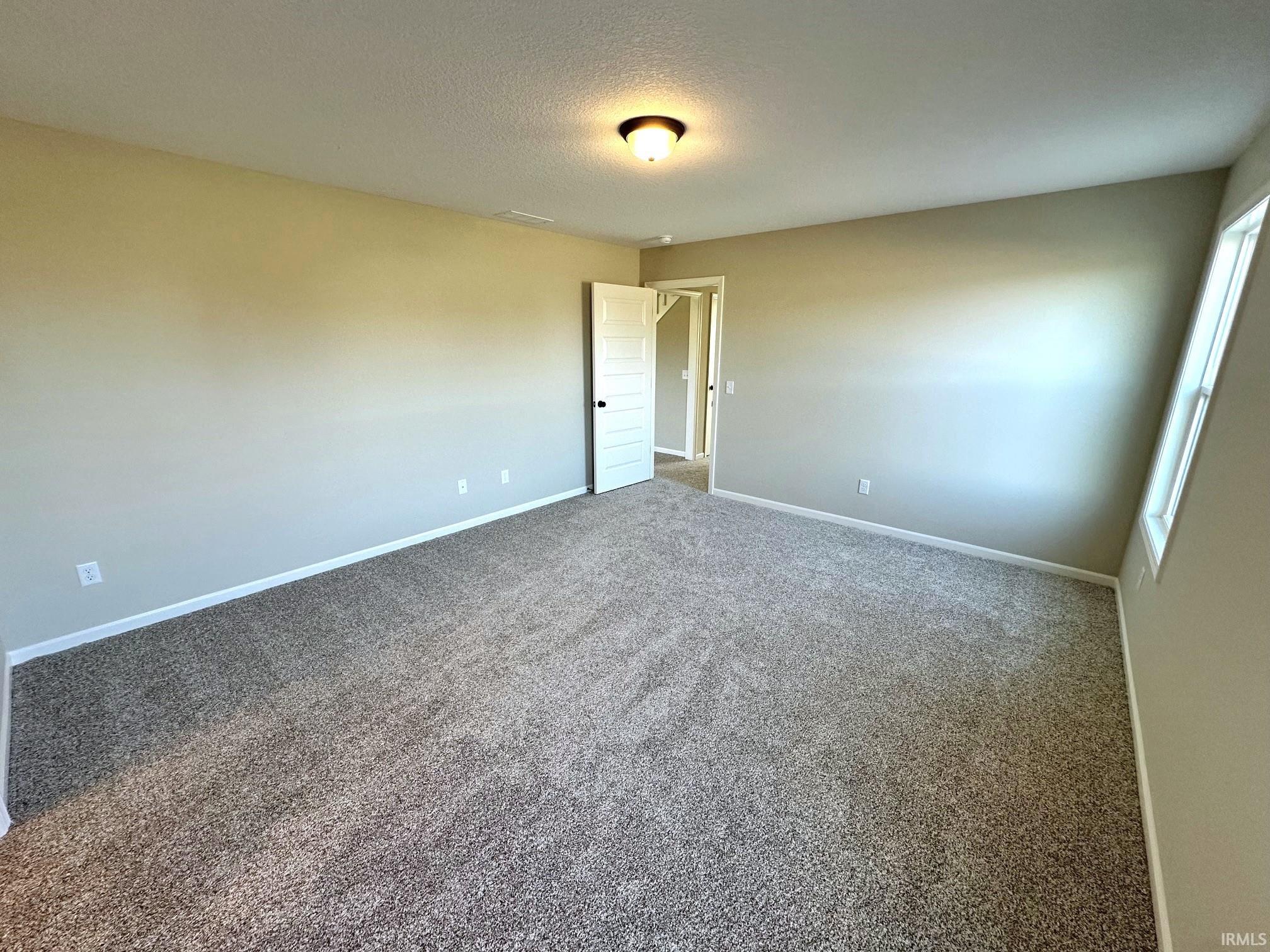 Spare room featuring dark carpet and a textured ceiling