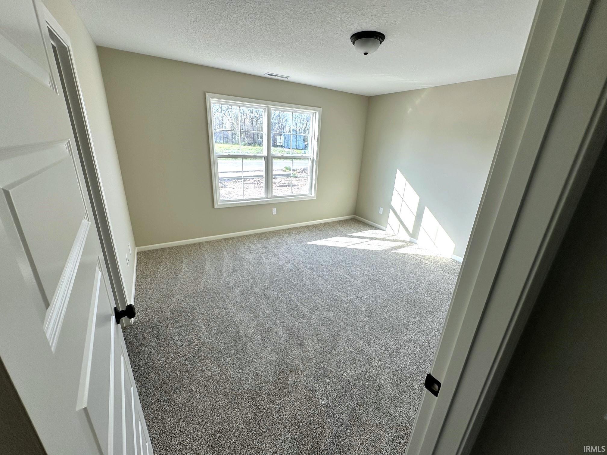 Unfurnished bedroom with light colored carpet and a textured ceiling