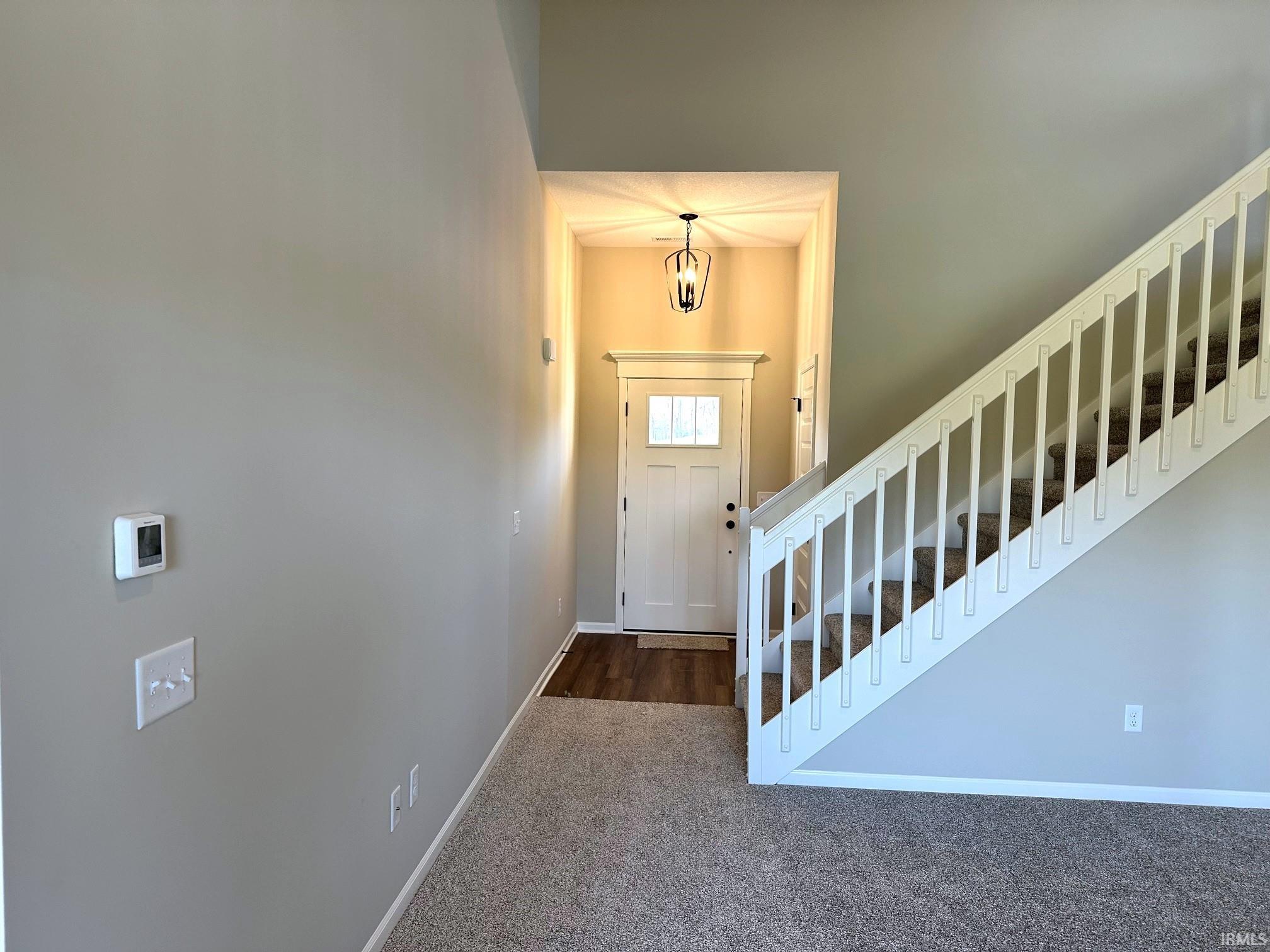 Entrance foyer featuring stairs and dark carpet