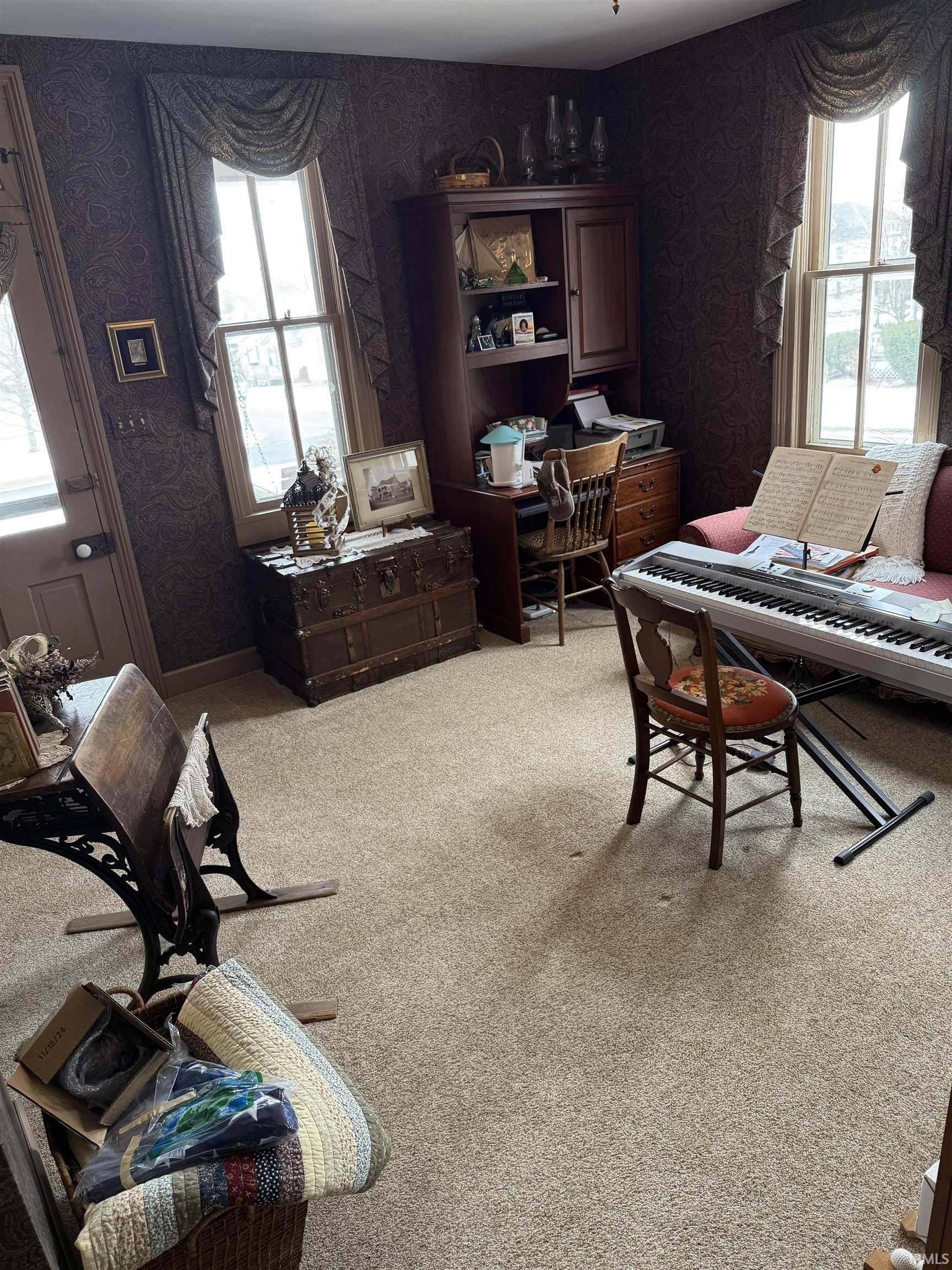 Living room featuring wallpapered walls, healthy amount of natural light, and light colored carpet