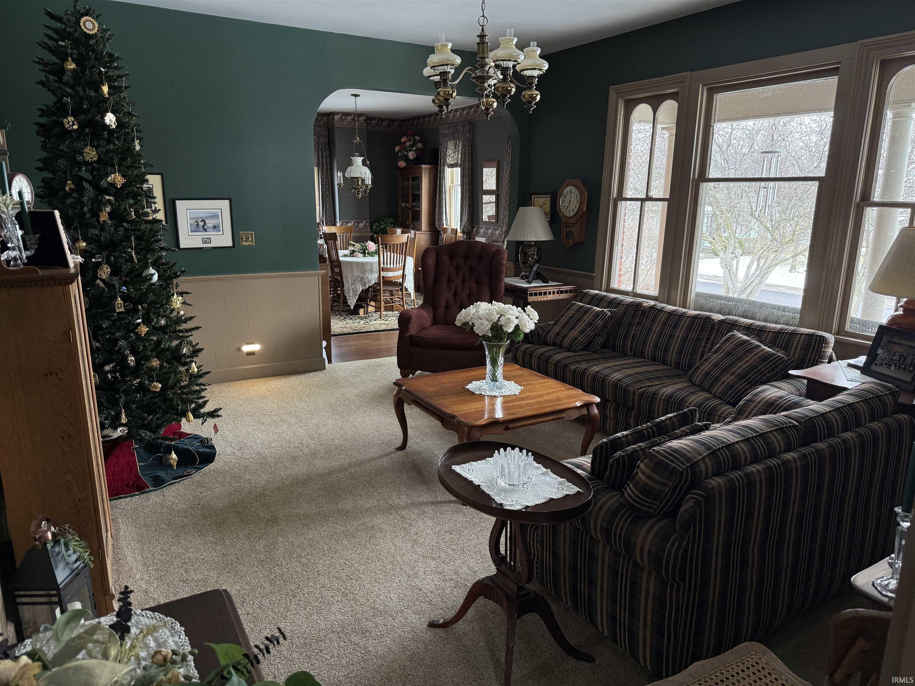 Living room with wainscoting, a chandelier, carpet flooring, and arched walkways