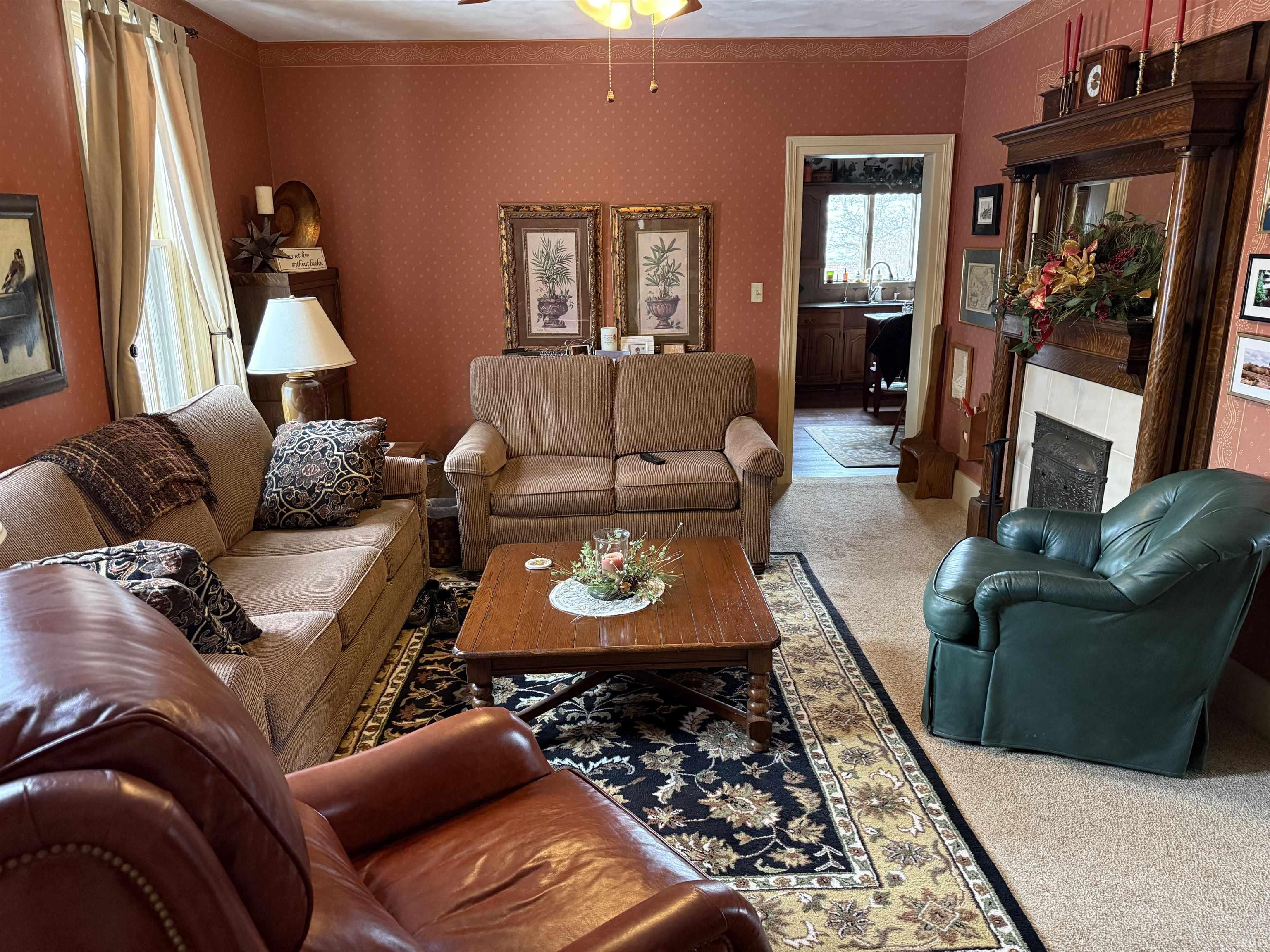 Carpeted living area featuring a tiled fireplace, wallpapered walls, a ceiling fan, and ornamental molding