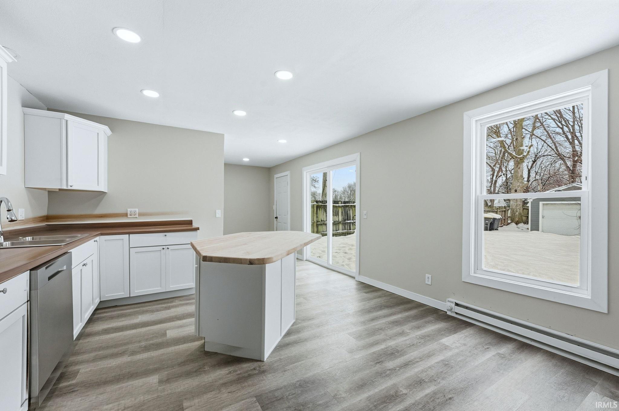 Kitchen featuring wood counters, white cabinetry, a kitchen island, recessed lighting, and dishwasher