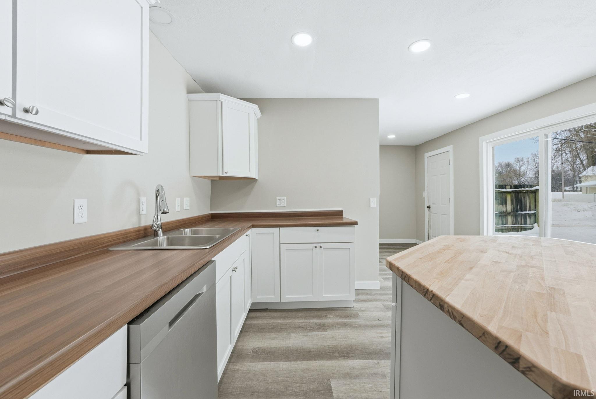 Kitchen featuring butcher block countertops, recessed lighting, stainless steel dishwasher, white cabinets, and light wood-type flooring
