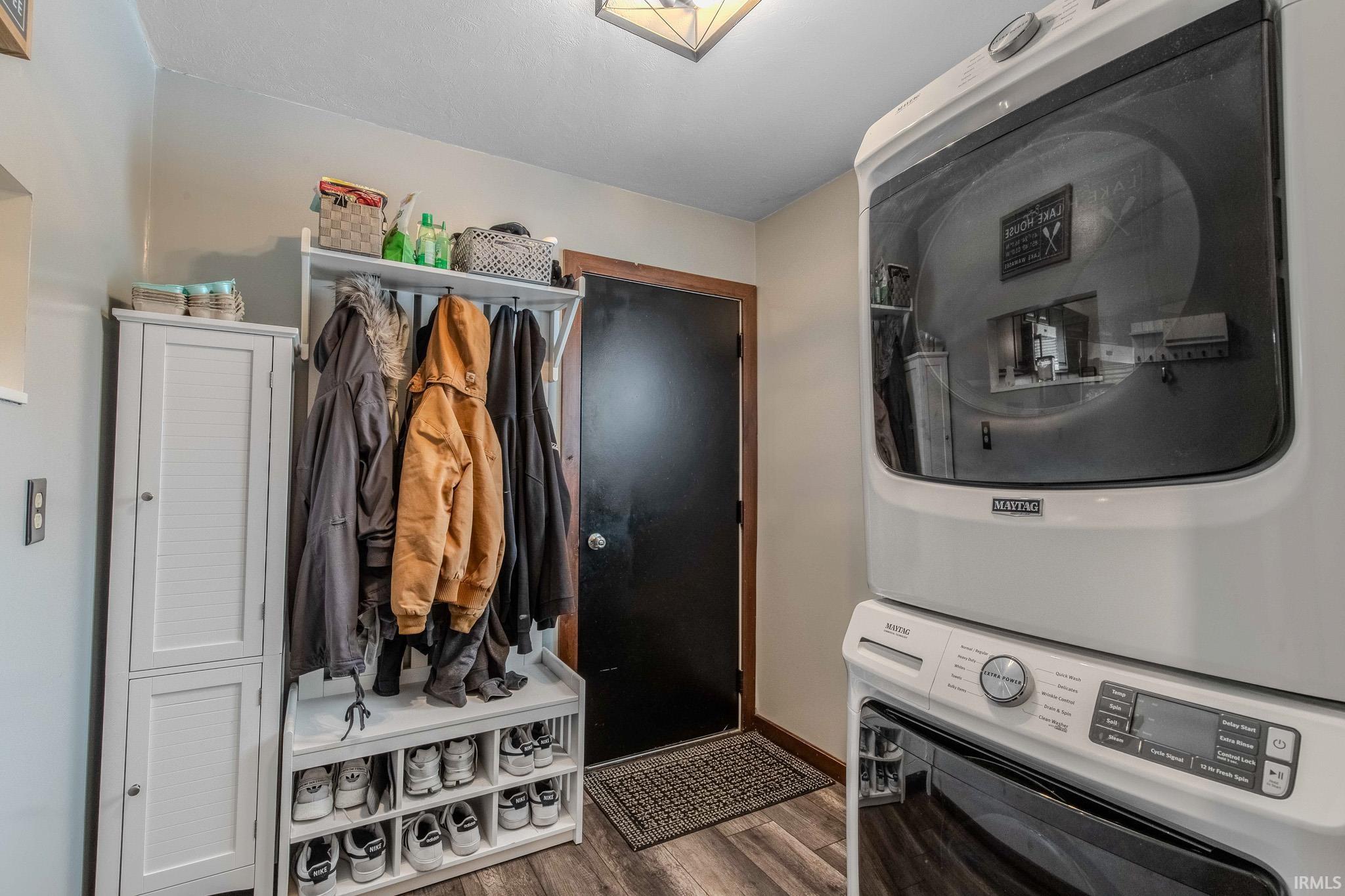 Laundry room featuring dark wood-style floors and stacked washing machine and dryer