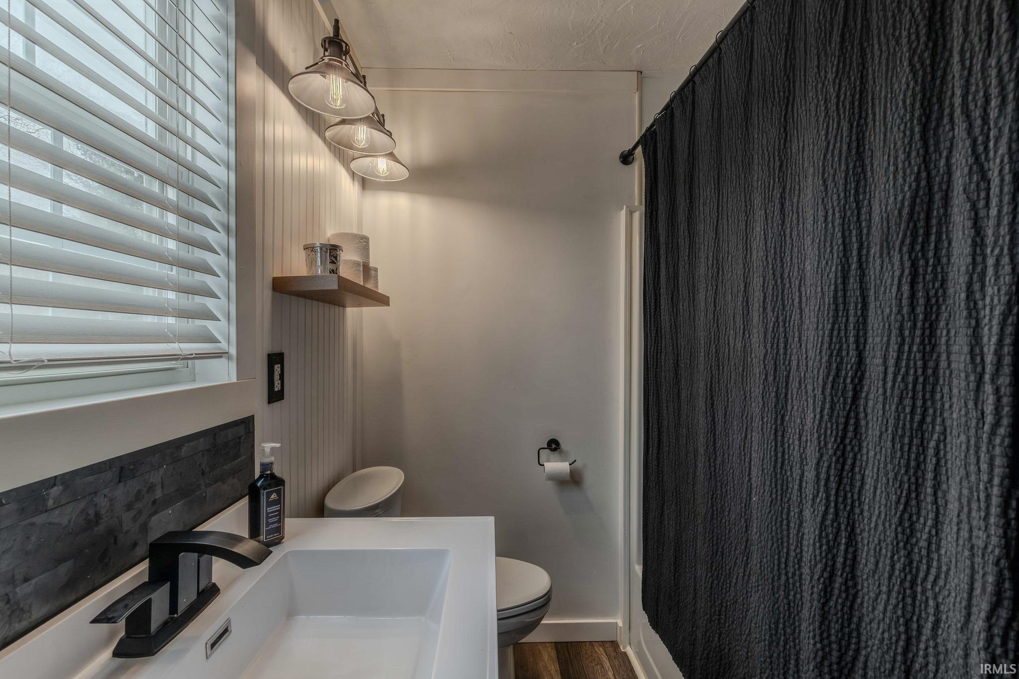 Bathroom with a shower with curtain, vanity, and dark wood-type flooring